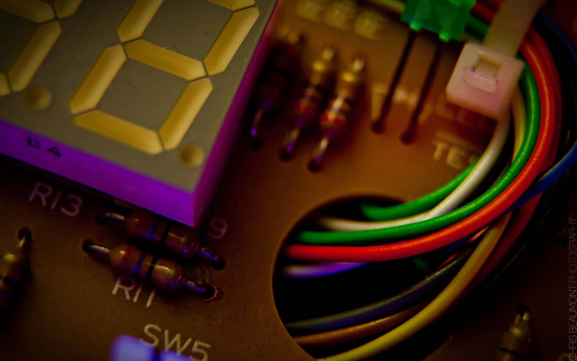 Electronics 桌布 壁紙 — 發光數碼顯示屏和彩色電線在帶有標籤組件的電路板上的特寫。