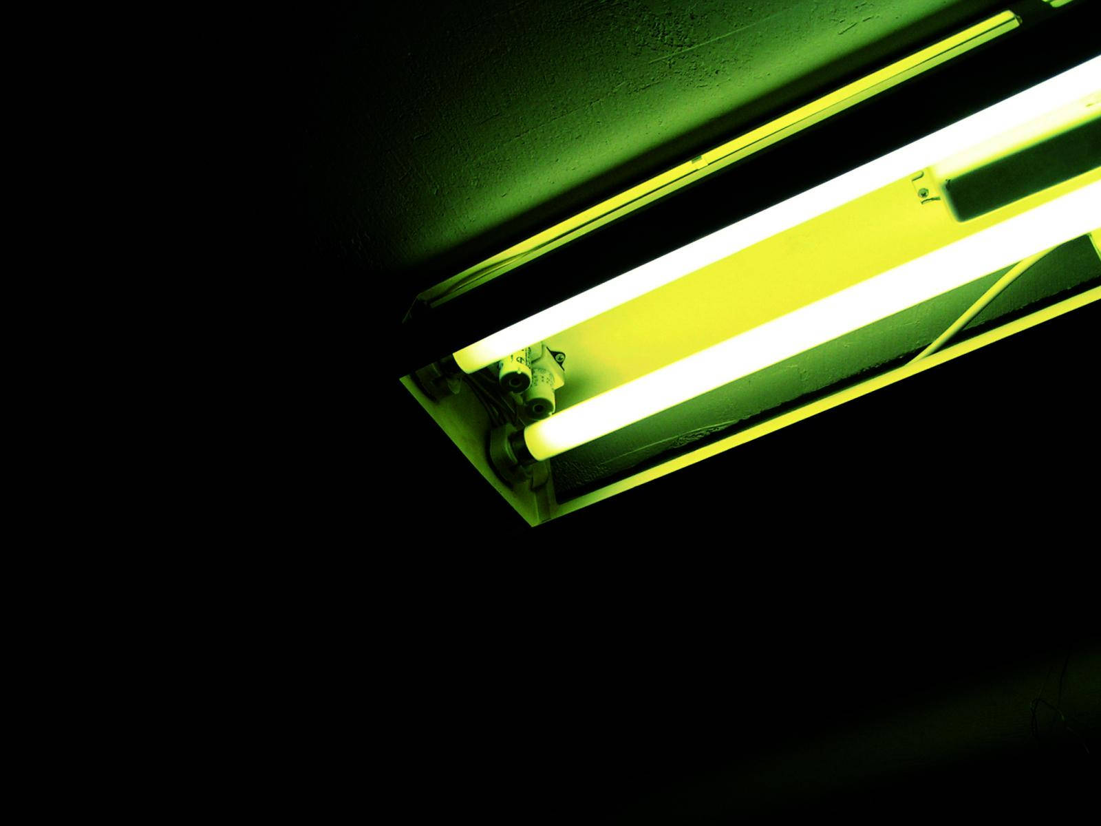 在黑暗房間中發出綠黃色光芒的明亮螢光燈管。