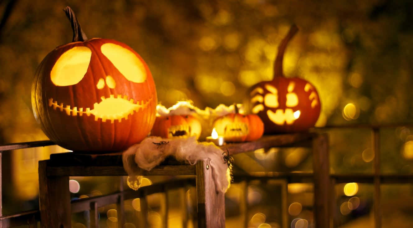 Halloween Props 桌布 壁紙 — 發光的傑克南瓜燈，縫合的嘴巴和大眼睛，放在木製欄杆上，背景是溫暖的散景。