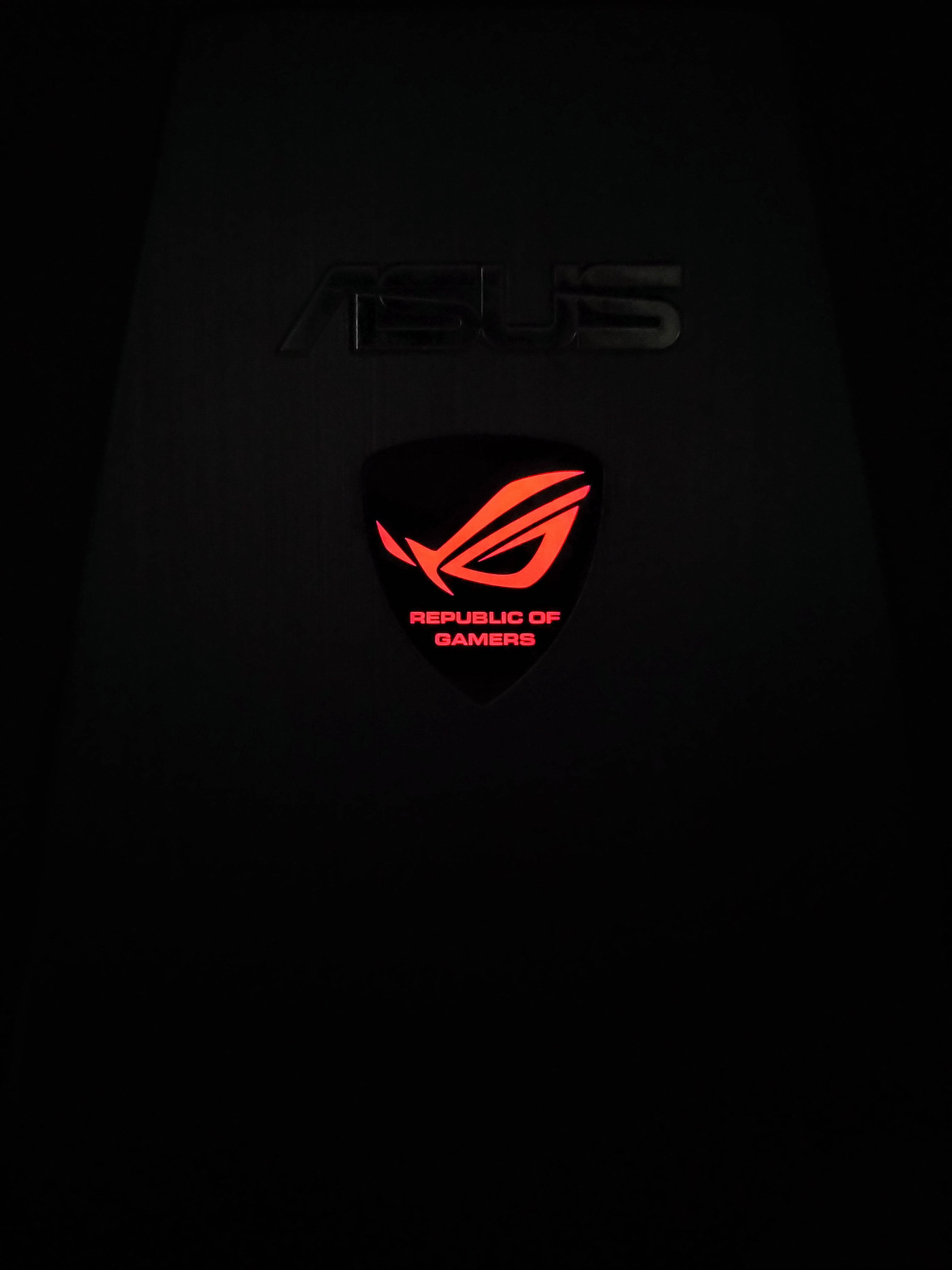 Gaming Logos 桌布 壁紙 — 發光的紅色ASUS ROG標誌在黑暗表面上照亮，營造出極簡科技氛圍。