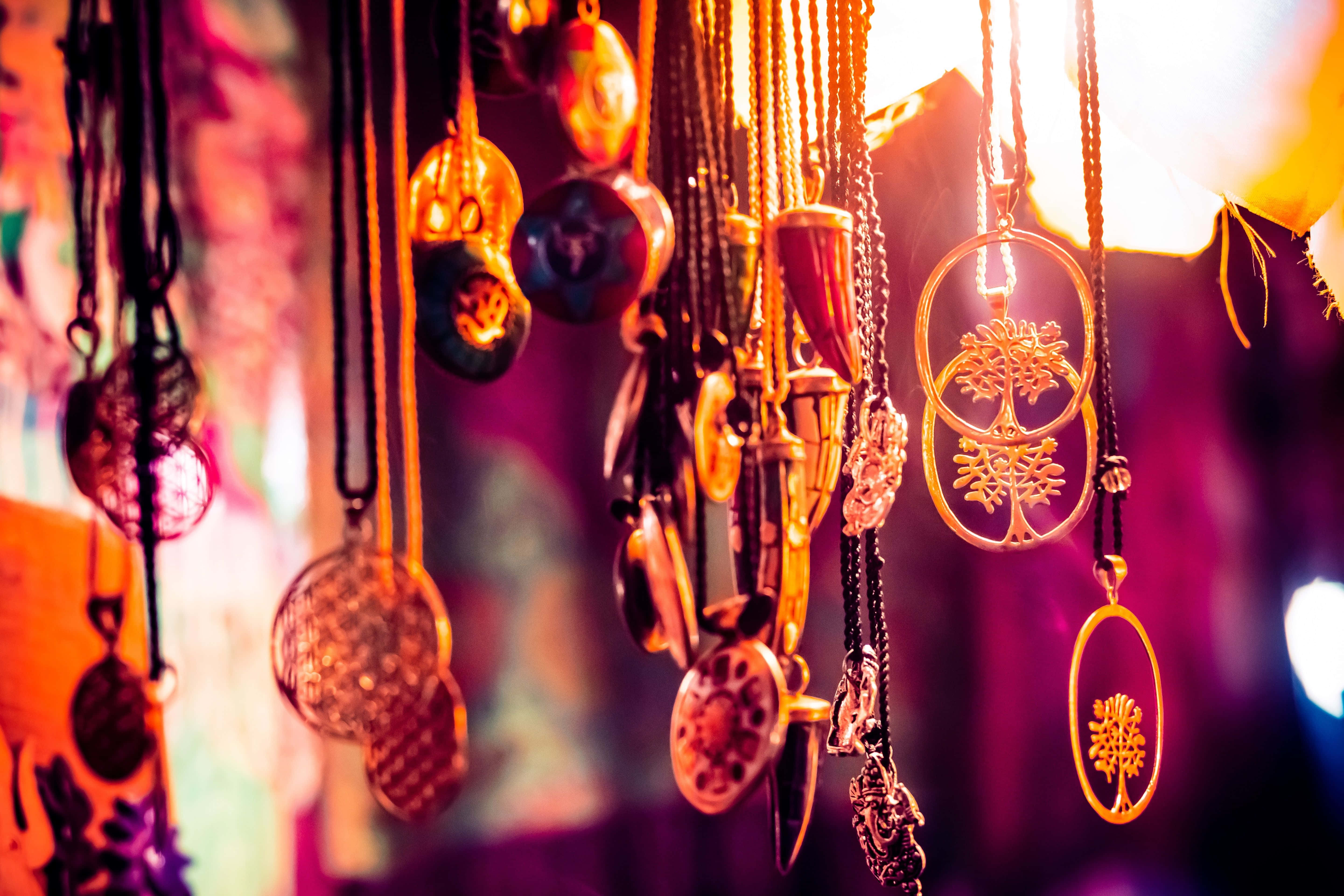 Accessory 桌布 壁紙 — 發光的金色和紫色吊墜項鍊在溫暖的散景背景下以柔焦懸掛。