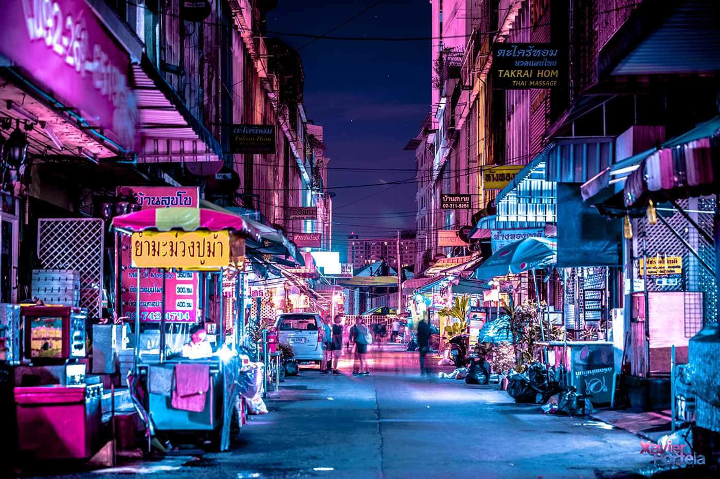 夜晚霓虹燈照亮的泰國街市，閃爍的招牌和小販。