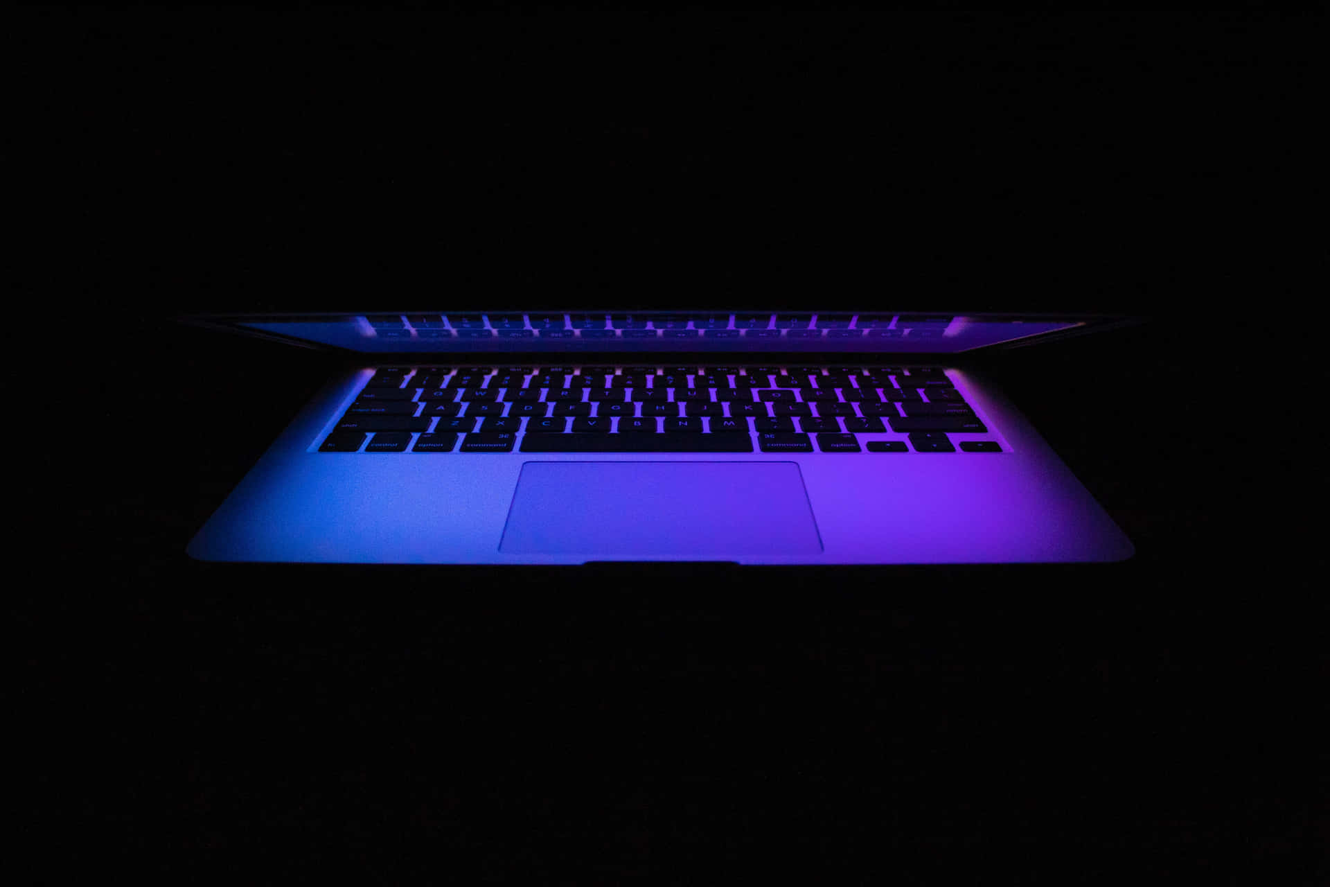 筆記型電腦在黑暗中發出藍色和紫色背光