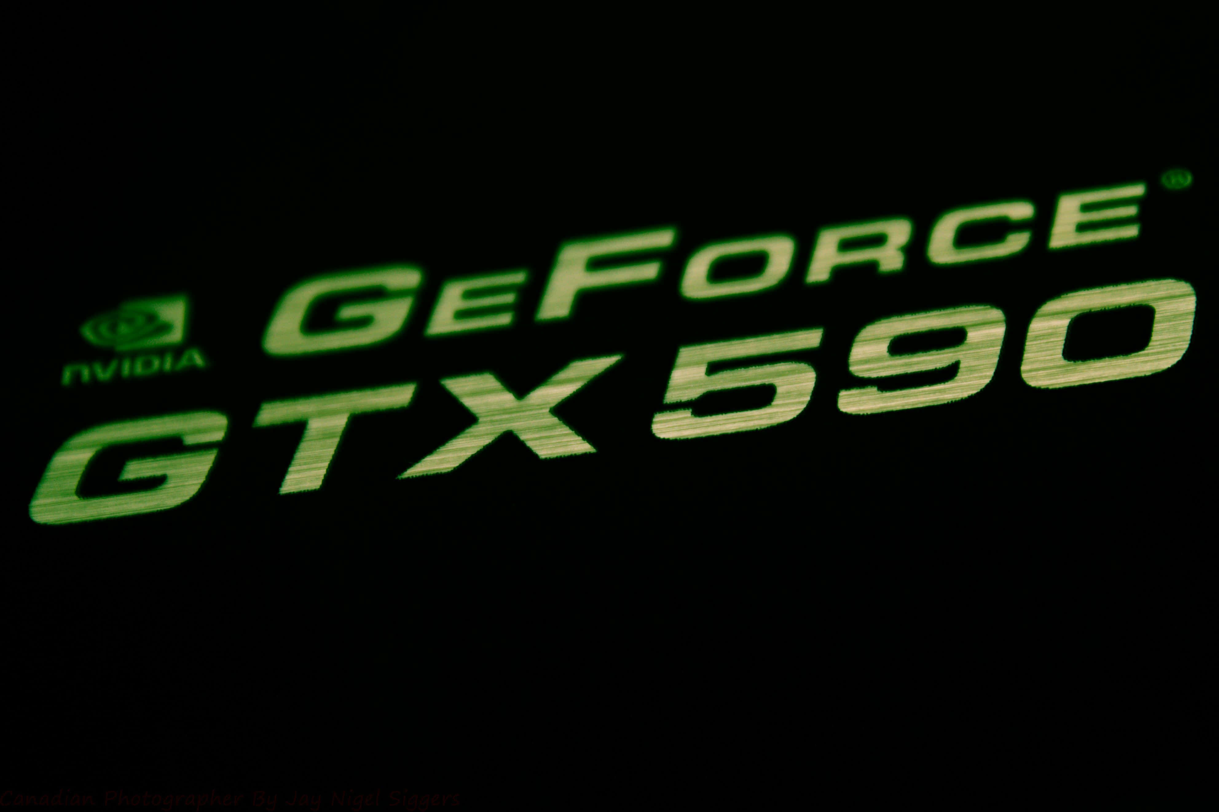 Nvidia 4K UHD GTX 590 壁紙 — 發光綠色NVIDIA GeForce GTX 590標誌，在漆黑背景上亮起。