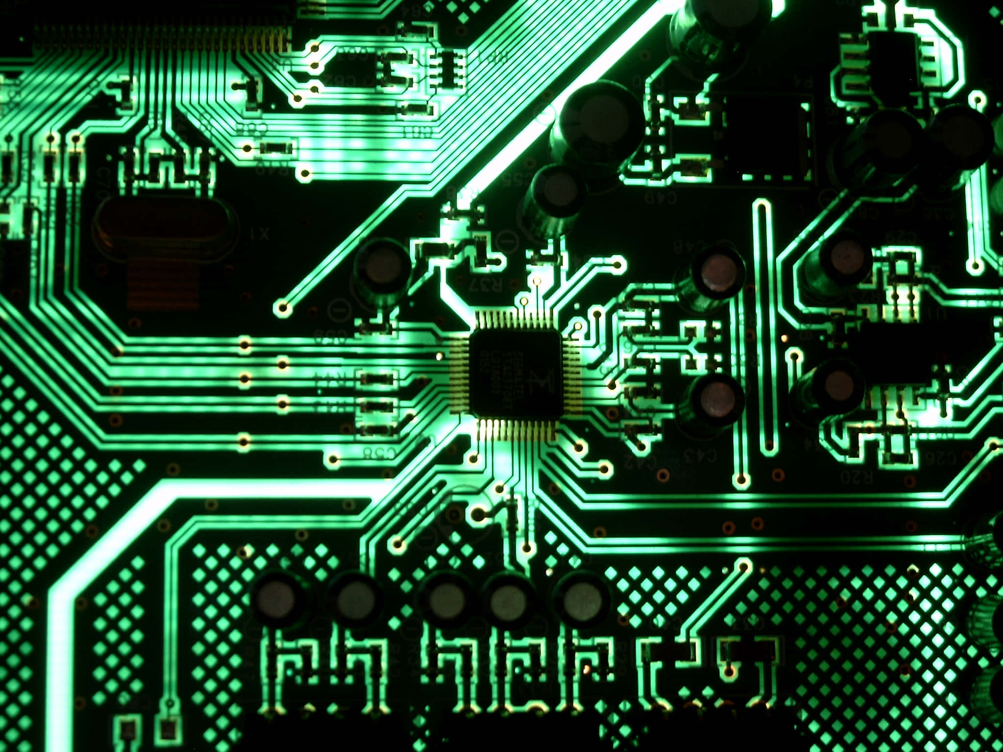 Electronics 桌布 壁紙 — 發光綠色電路板的特寫，具有複雜的路徑和元件，在戲劇性的燈光下。