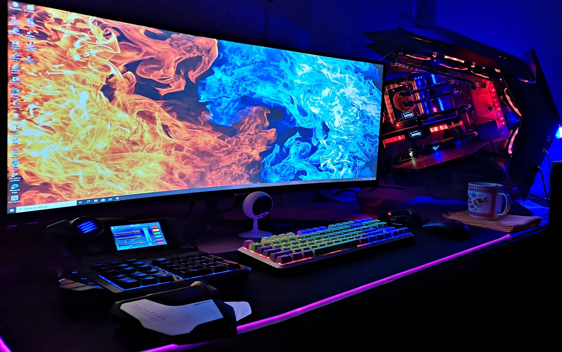 在紫色燈光下帶有 RGB 鍵盤和發光 PC 的遊戲桌。