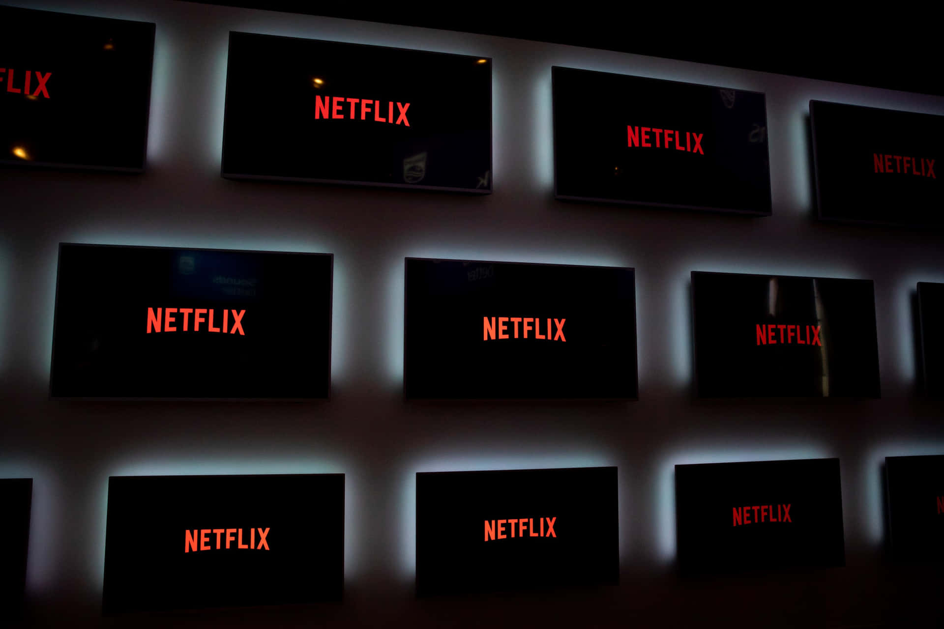 在黑暗的房間中，帶有藍色背光的 Netflix 螢幕牆發光。