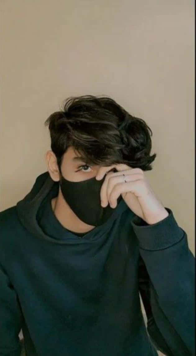 身穿黑色連帽衫的年輕男子掀起黑色口罩，露出一隻眼睛。