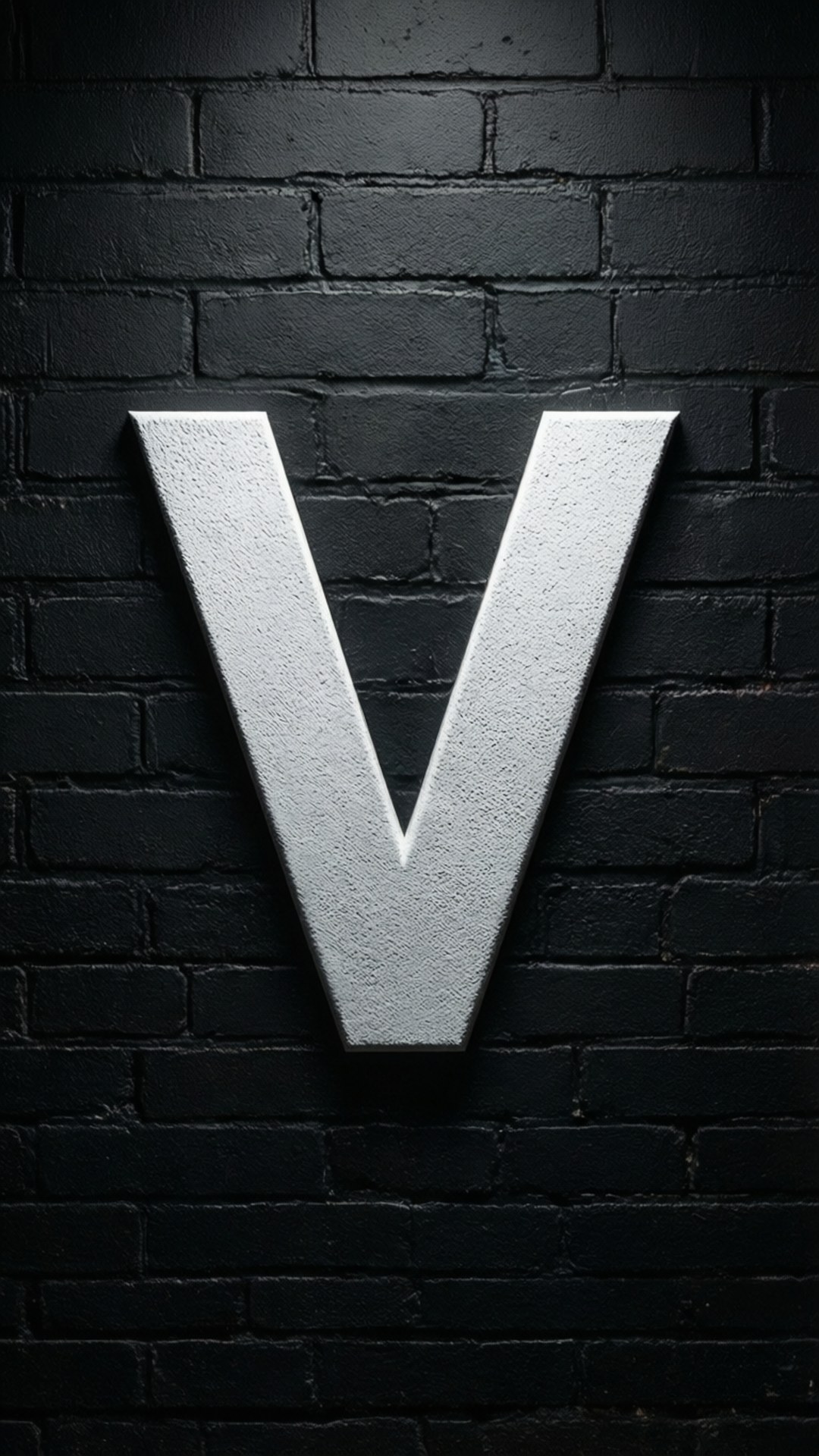 白V磚牆 壁紙 — 一個大型金屬字母V在戲劇性的聚光燈下，大膽地矗立在紋理黑色磚牆前。