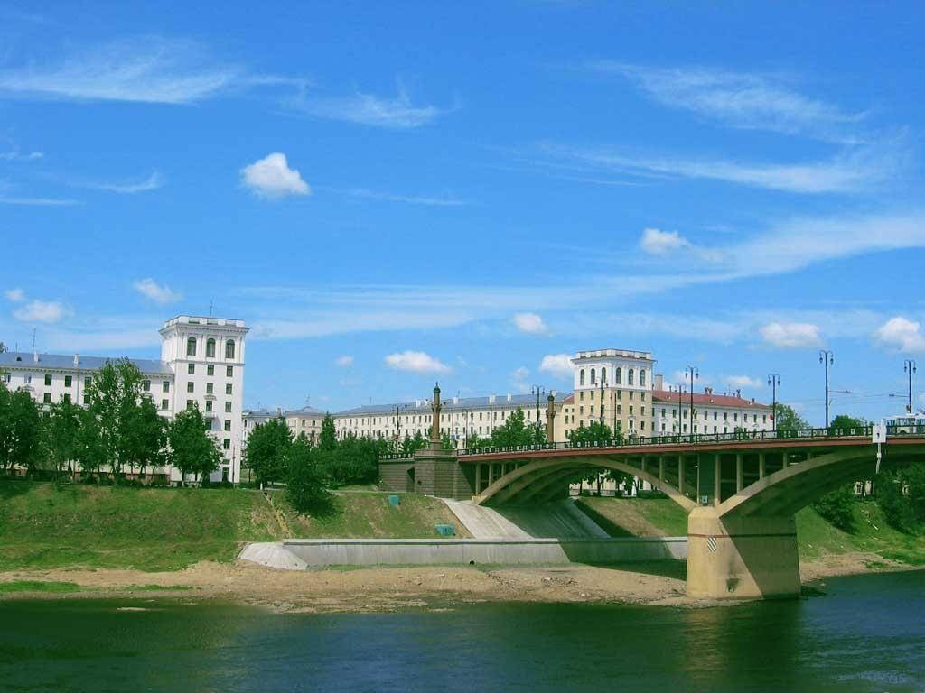 白俄羅斯白色建築群 壁紙 — 一座宏偉的石橋拱跨在平靜的河面上，上方是明亮的藍天，點綴著蓬鬆的白雲。