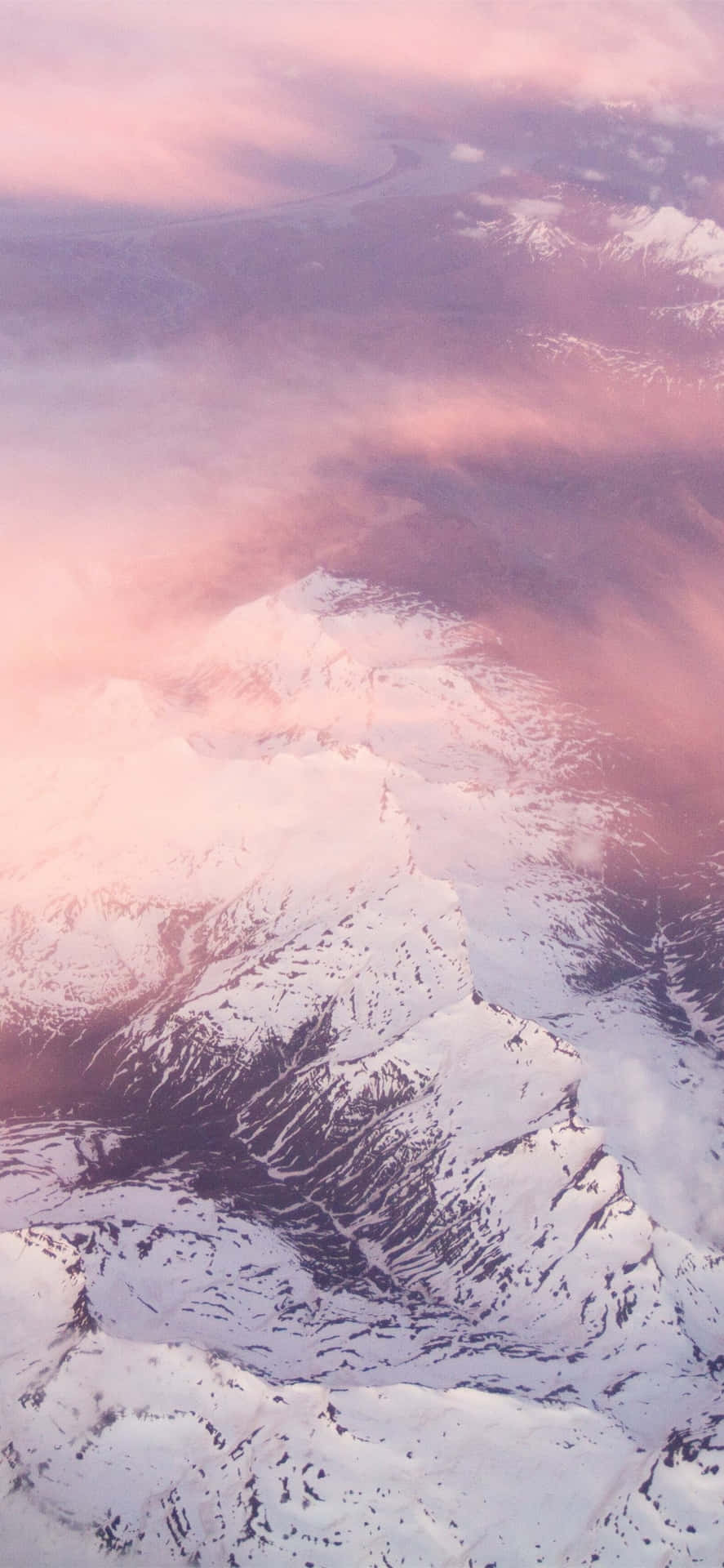 從上方看粉紅和紫色暮雲下的雪峰。