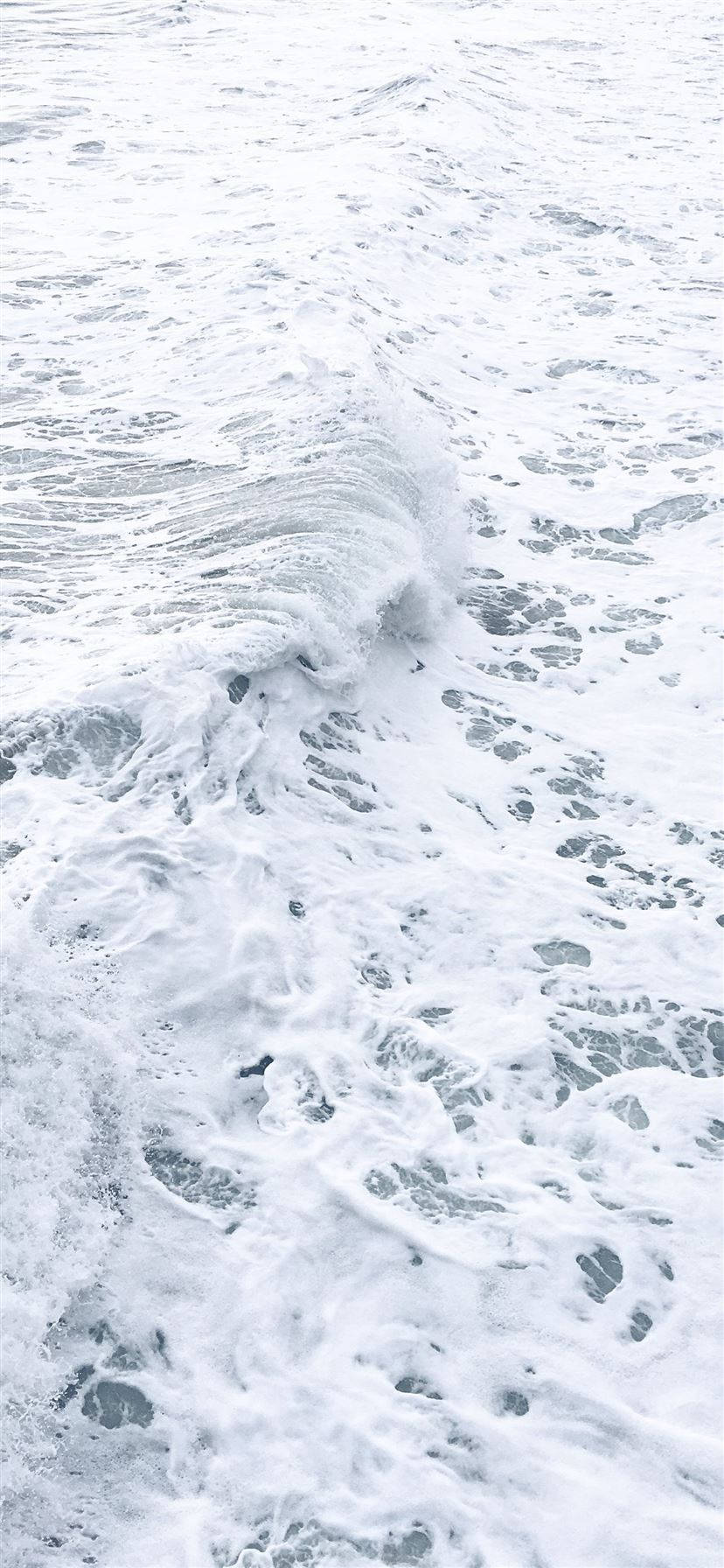 白底iPhone海浪泡沫 壁紙 — 冰冷灰藍色海洋上，泡沫海浪拍打著白色泡沫的特寫。
