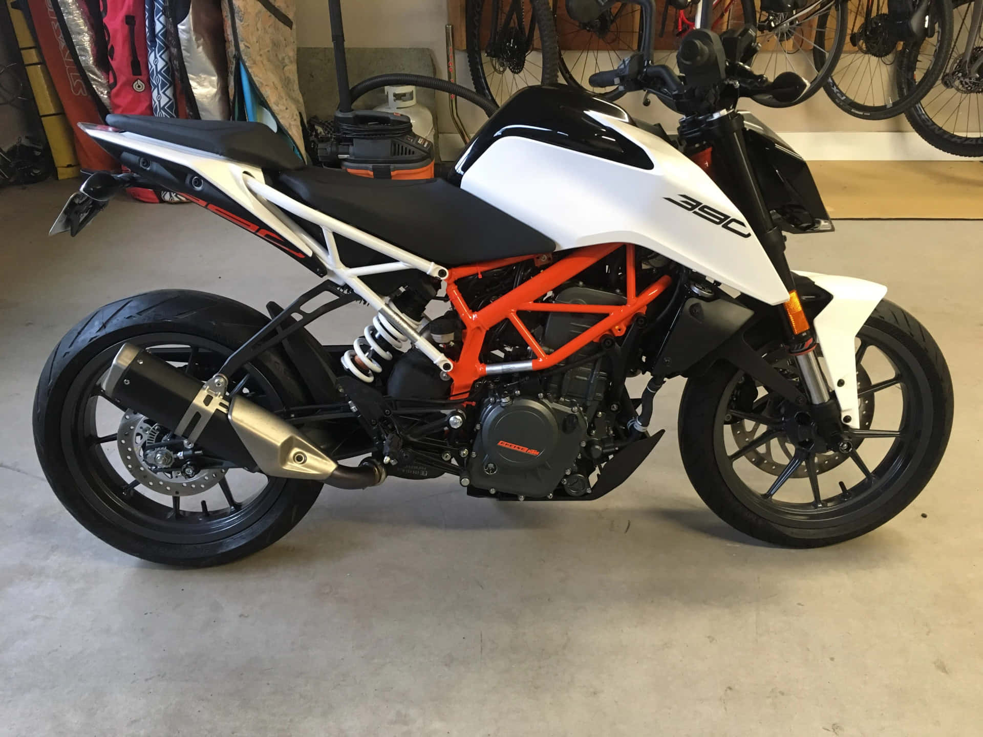 白色和橙色的KTM 390電單車停放在車庫中，牆上掛著單車。