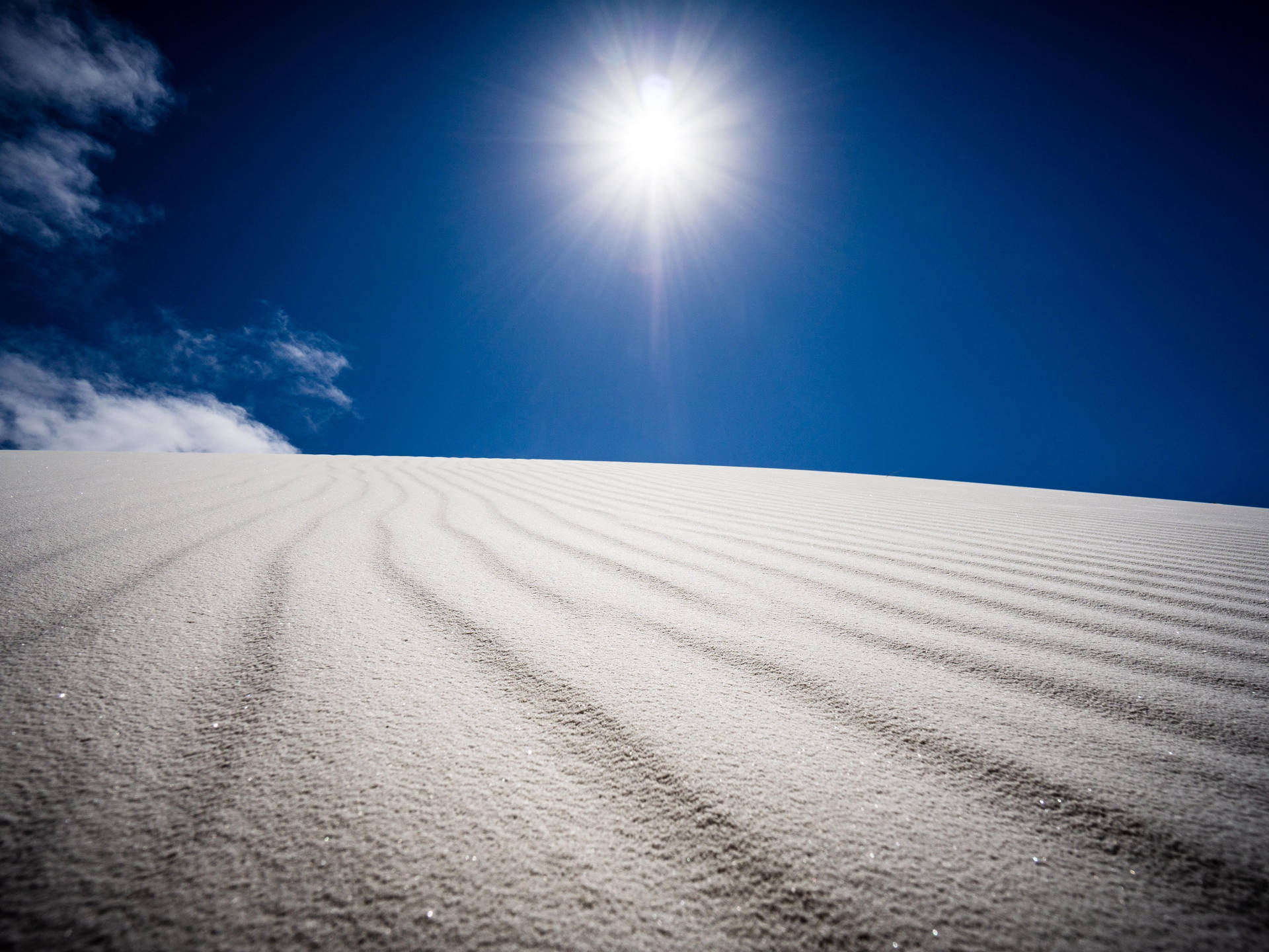 藍天白雲下陽光燦爛的雪沙丘