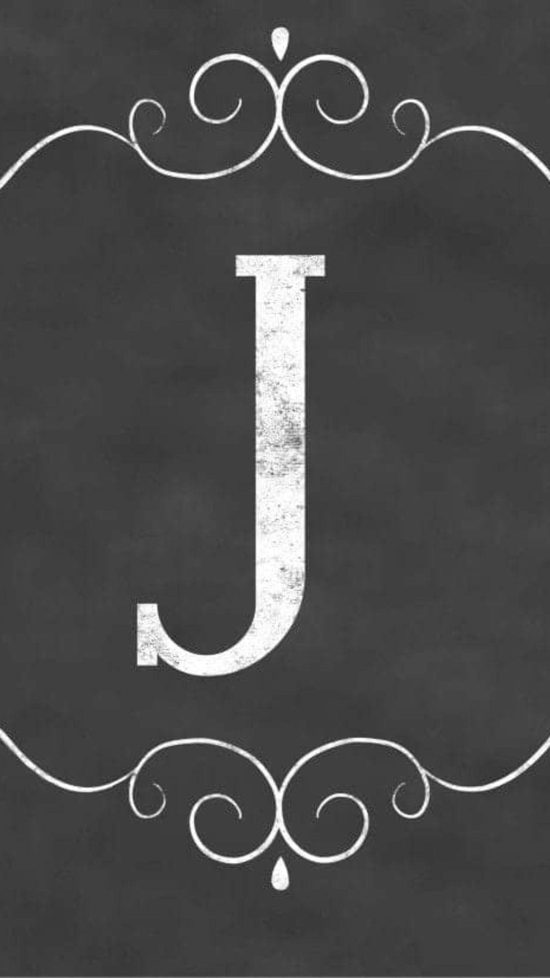 黑板上有白色字母J，以裝飾性漩渦框住。
