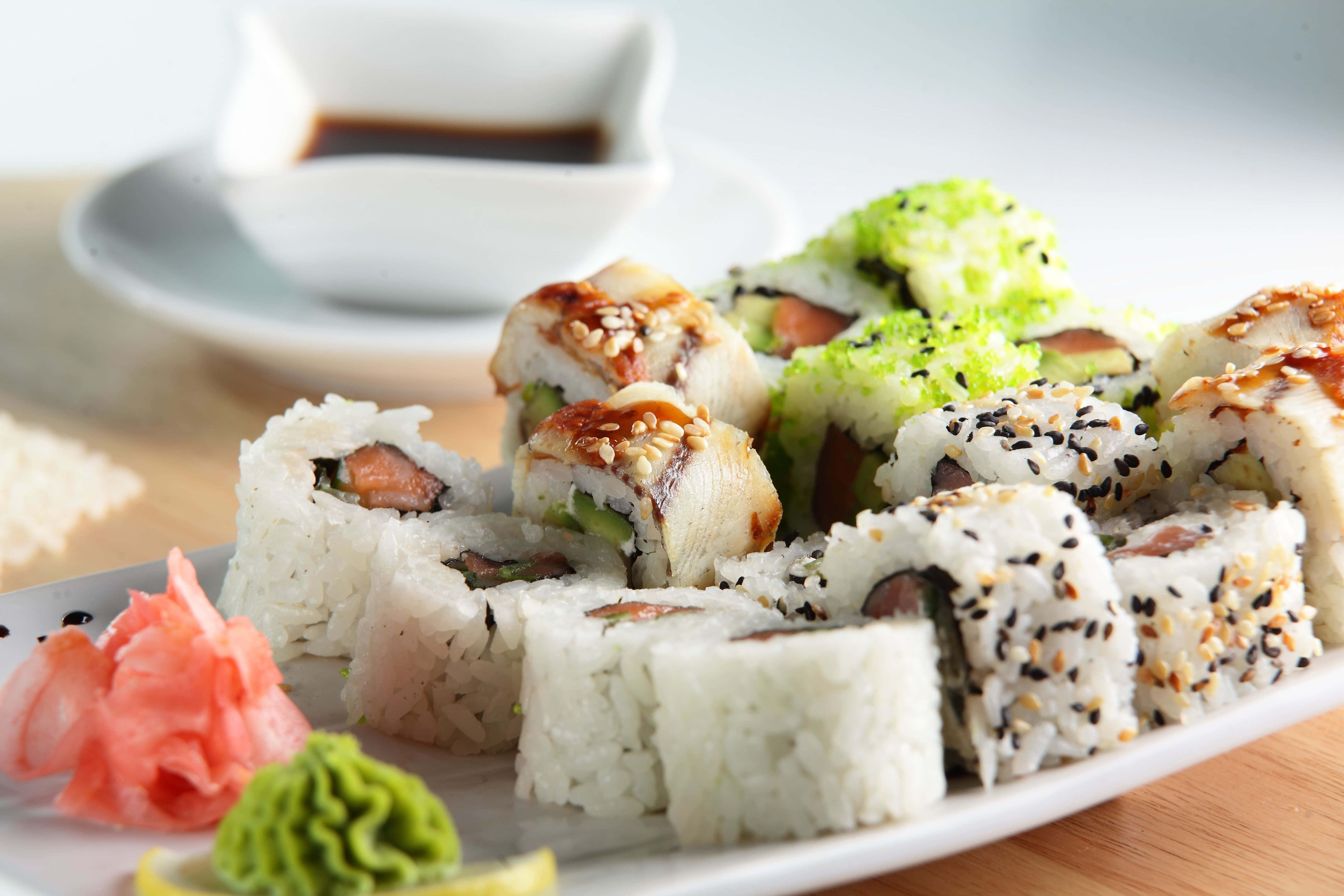 Sushi 桌布 壁紙 — 白碟上嘅雜錦壽司卷近鏡，配有芝麻、薑、Wasabi同醬油。