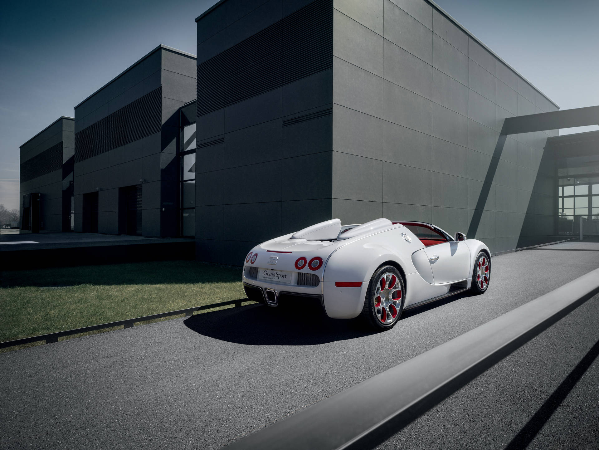 白色Bugatti Grand Sport開篷跑車停泊在現代建築旁。
