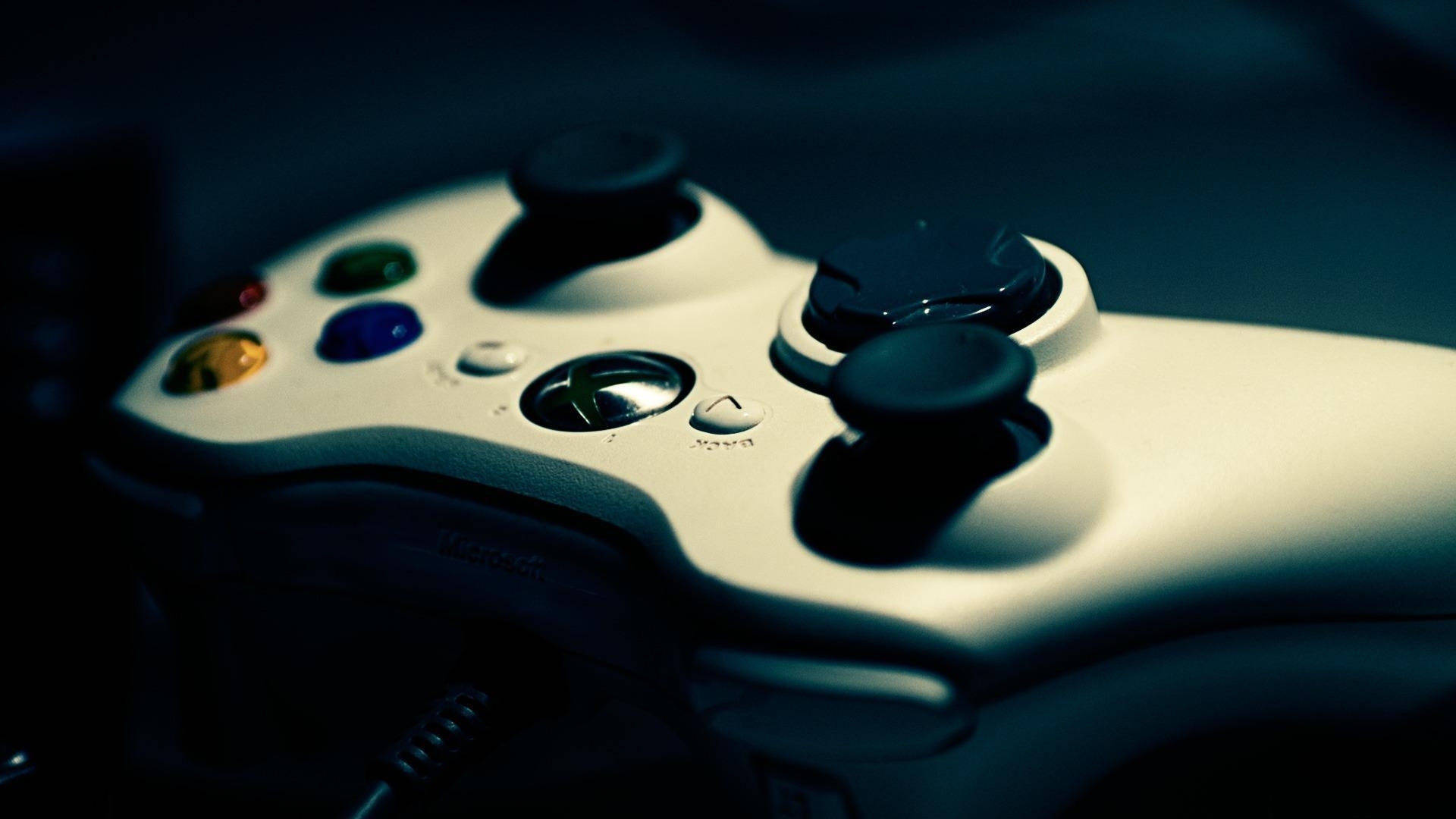 白色 Xbox 360 控制器，帶有彩色按鈕和黑色搖桿，在昏暗的藍光中。