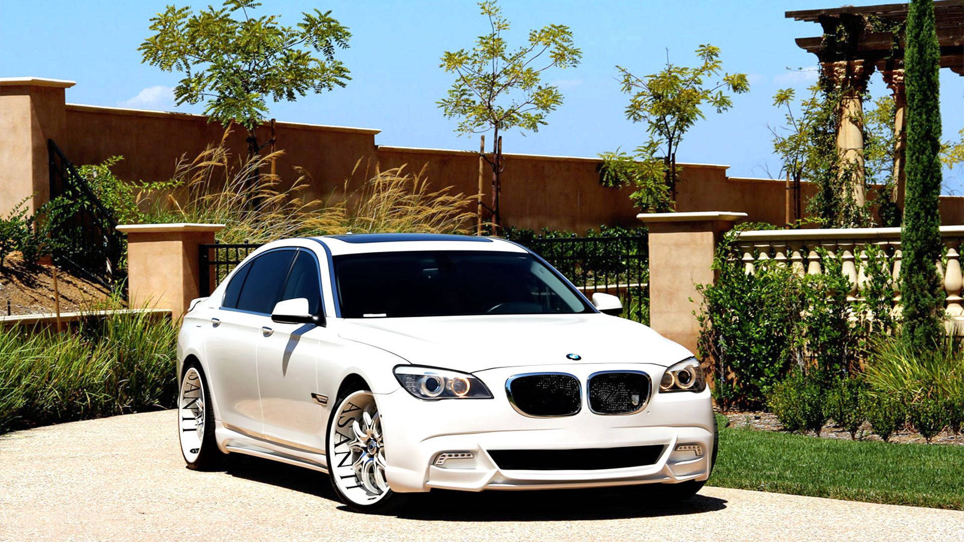 白色BMW房車停在碎石車道上，有花園和灰泥牆