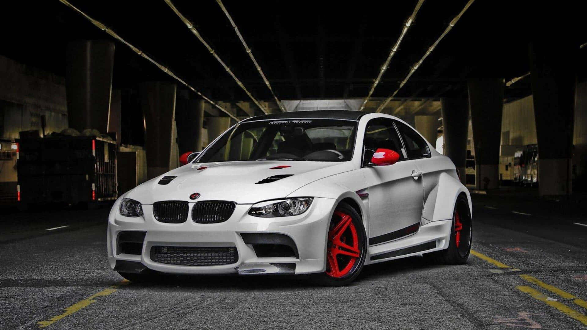 白色BMW M3 GT2 E92 1920x1080 M系列背景 壁紙 — 一輛白色BMW M3，帶有紅色點綴和定制輪圈，夜間停放在燈光昏暗的混凝土天橋下。