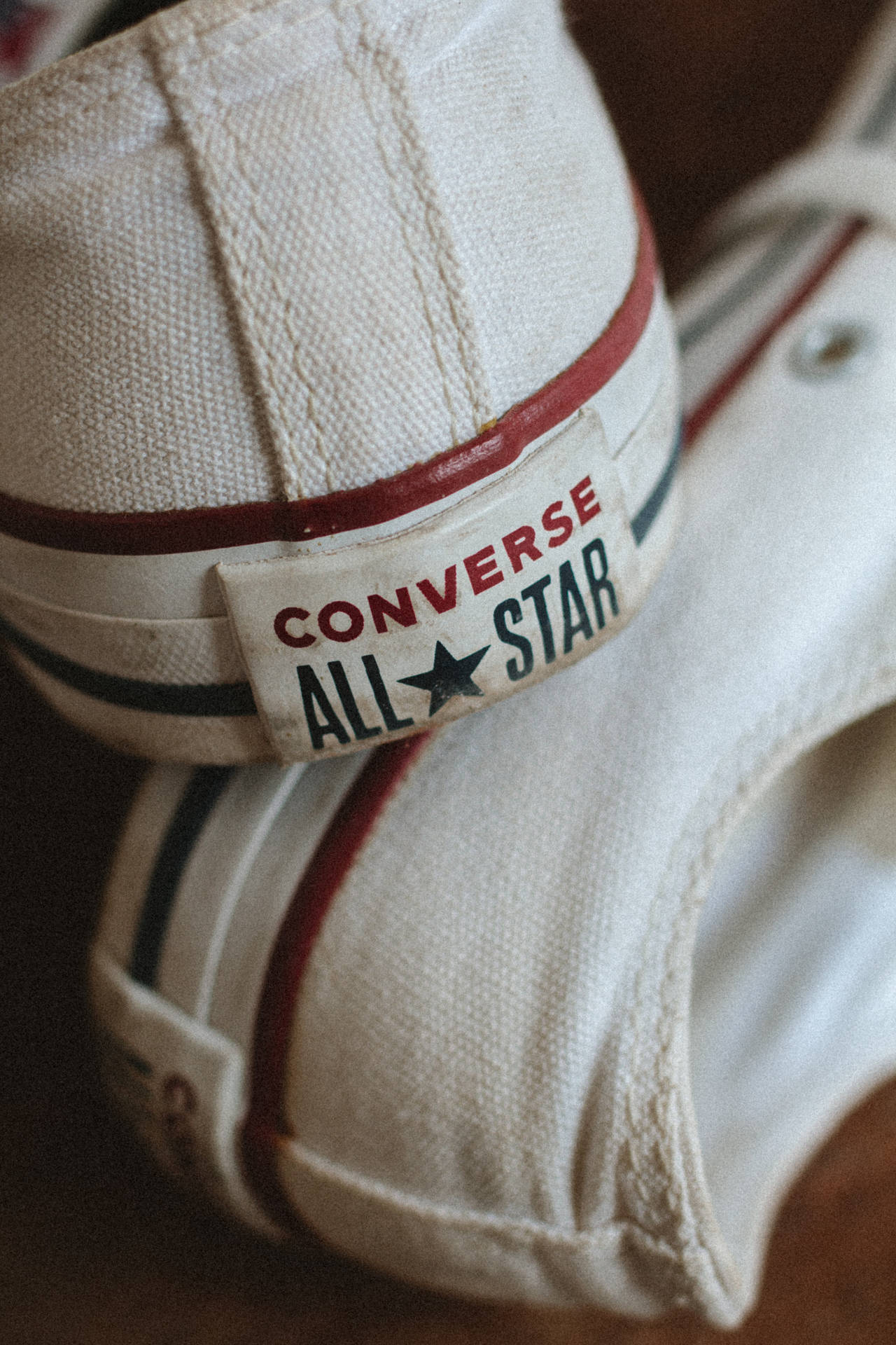 磨損的白色Converse All Star運動鞋，帶有紅色和黑色條紋。