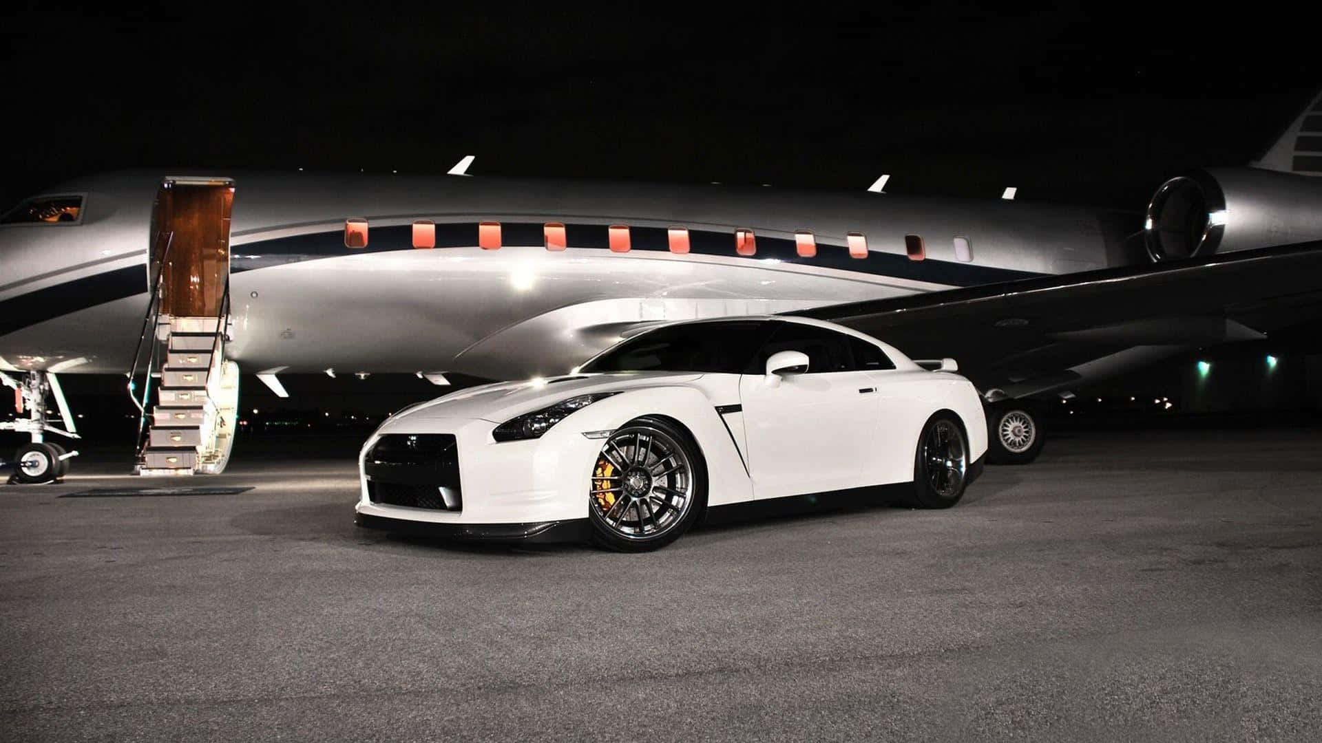 白色跑車夜間停泊在私人飛機旁。