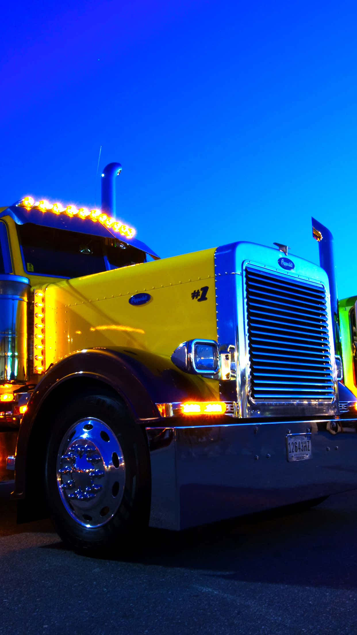 白色Kenworth卡車配深藍背景 壁紙 — 一輛充滿活力的黃色半掛卡車，配以閃爍的琥珀色燈光，在深藍色的暮色天空中格外醒目。