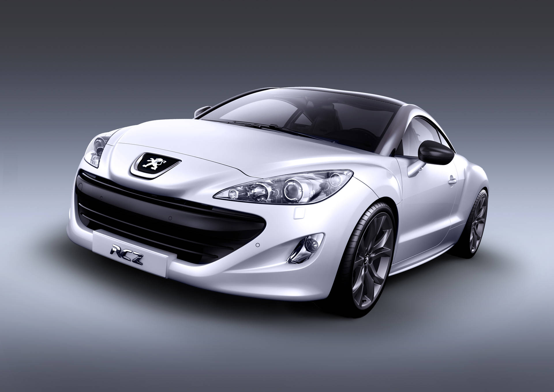 銀色Peugeot RCZ跑車在工作室燈光下，帶有黑色飾邊和合金輪圈。