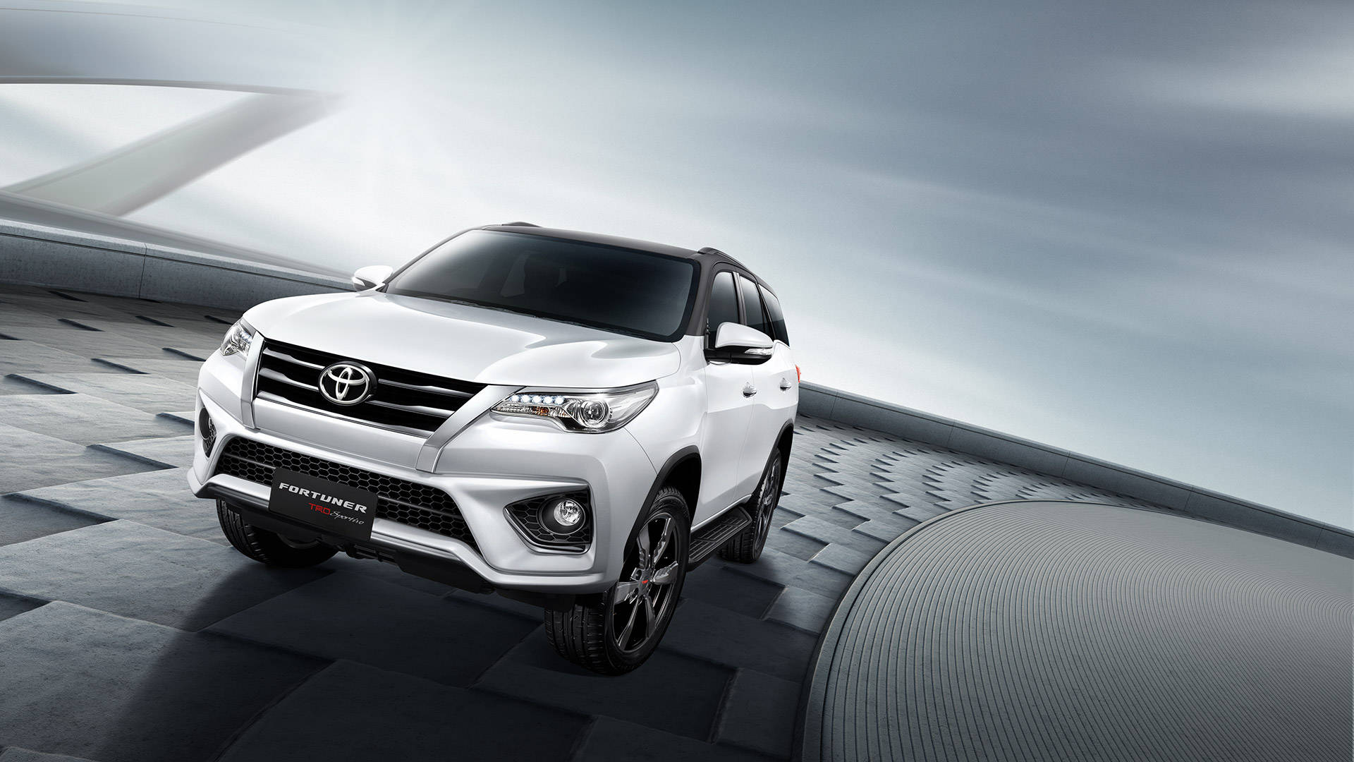 白色豐田 Fortuner SUV 在未來感灰色平台上，搭配戲劇性燈光。