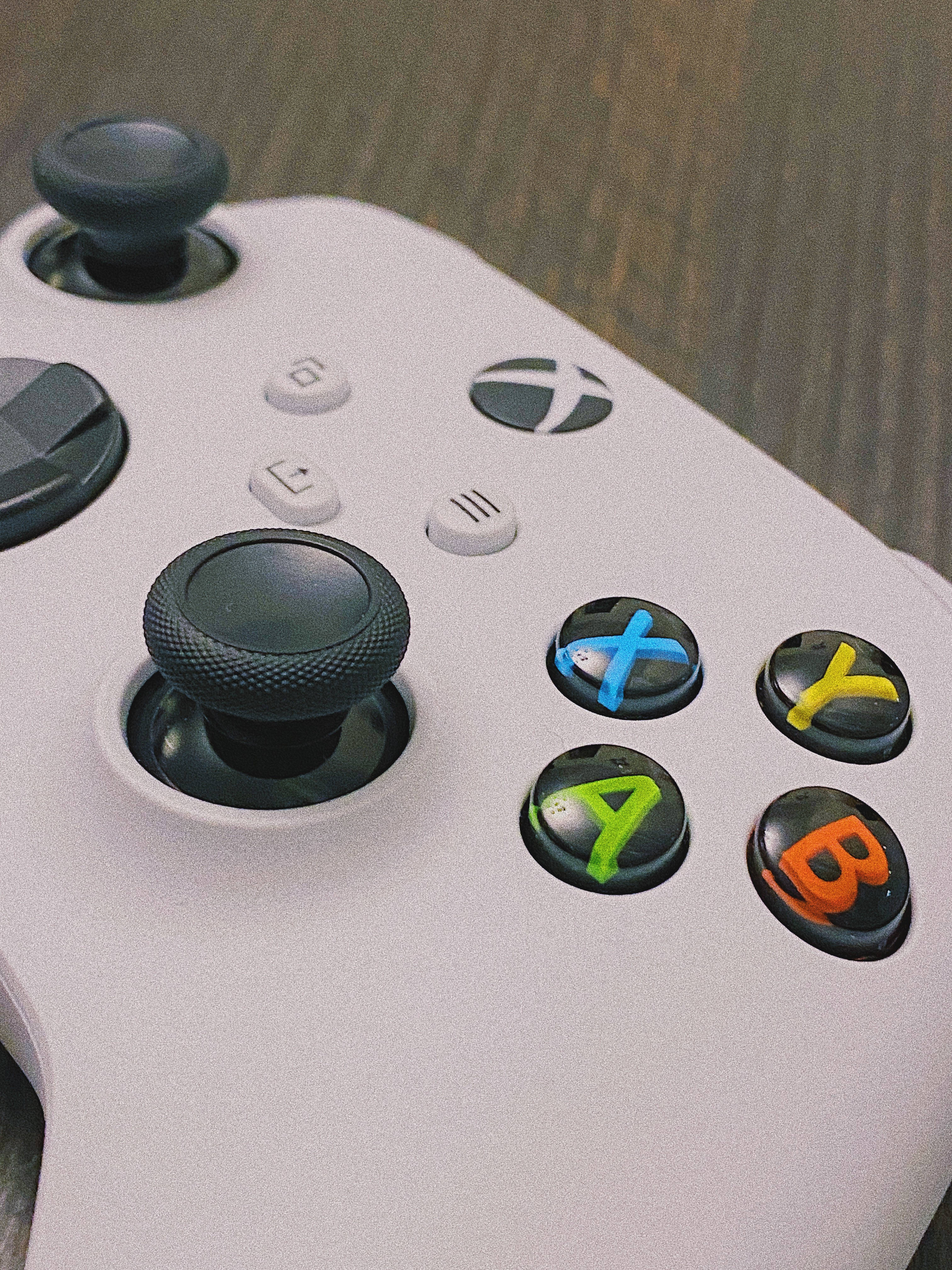 白色Xbox搖桿 壁紙 — 白色Xbox手掣特寫，帶有彩色ABXY按鈕，放置在木質表面上。