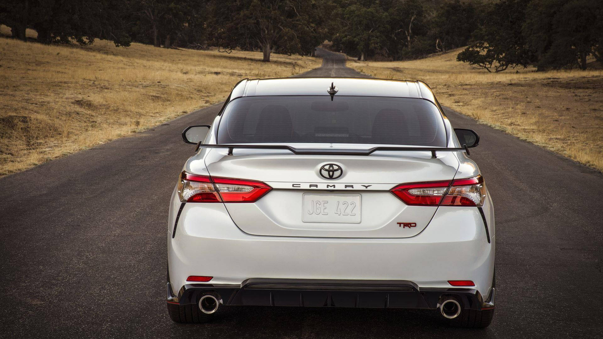 白色豐田Camry TRD房車在日落時分行駛在鄉村道路上。