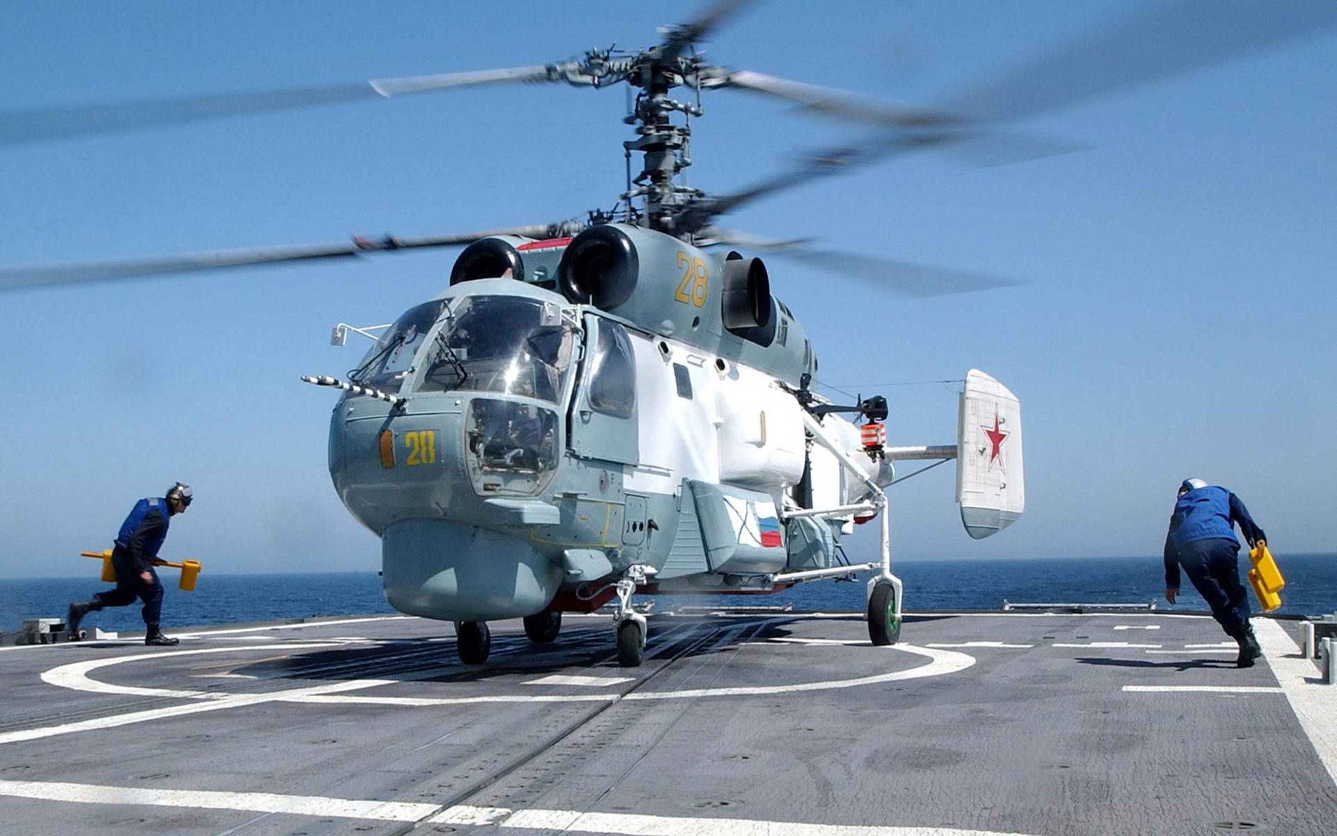軍用直升機在航空母艦甲板上，機組人員引導它。