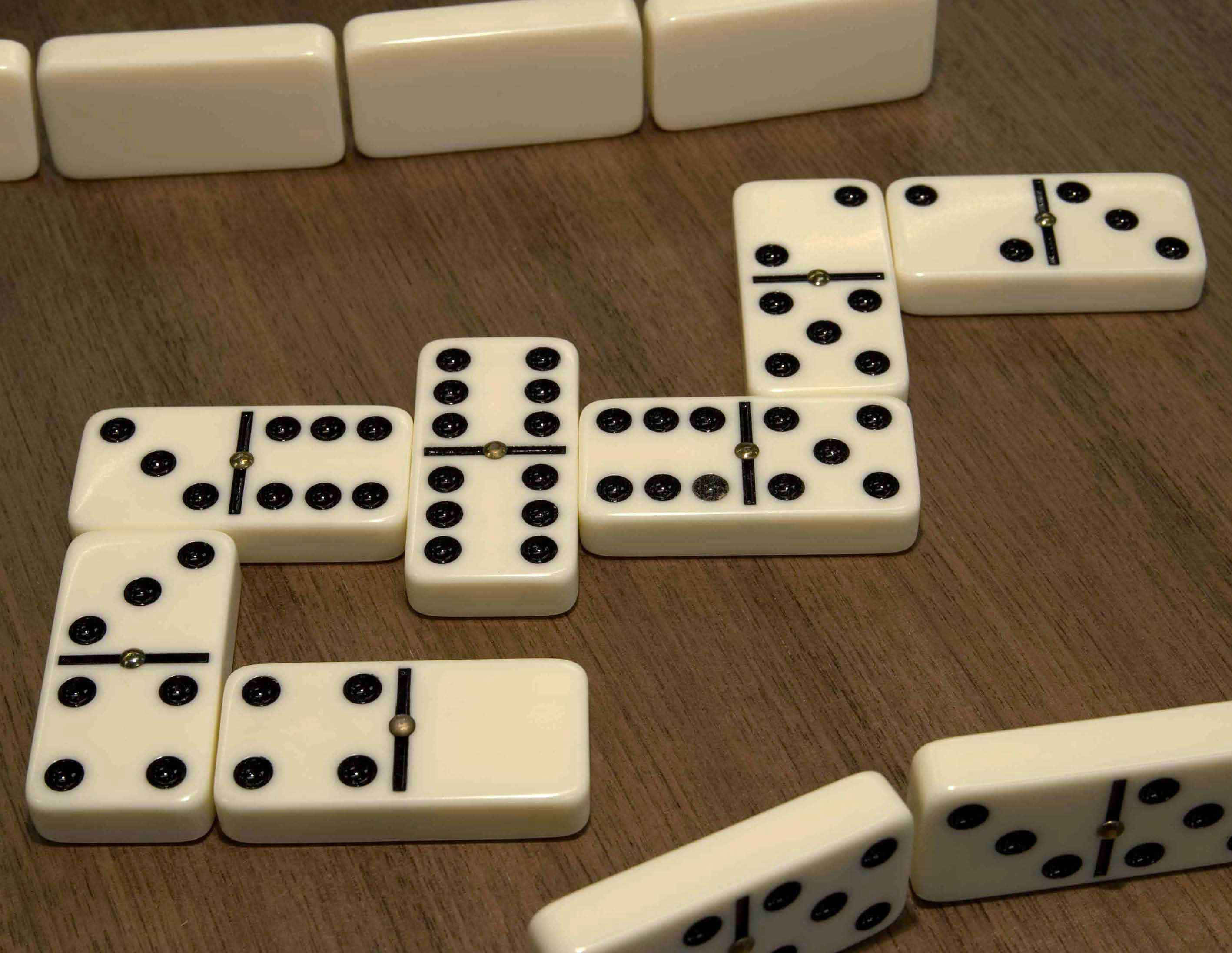 Domino 桌布 壁紙 — 白色多米諾骨牌帶有黑色圓點，以分散圖案排列在溫暖的木質桌面上。