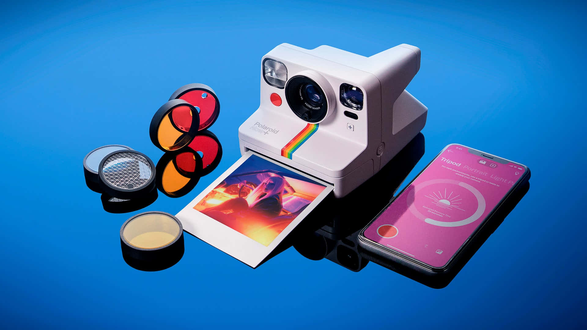 Polaroid相機連同照片和濾鏡，旁邊有智能手機，藍色背景