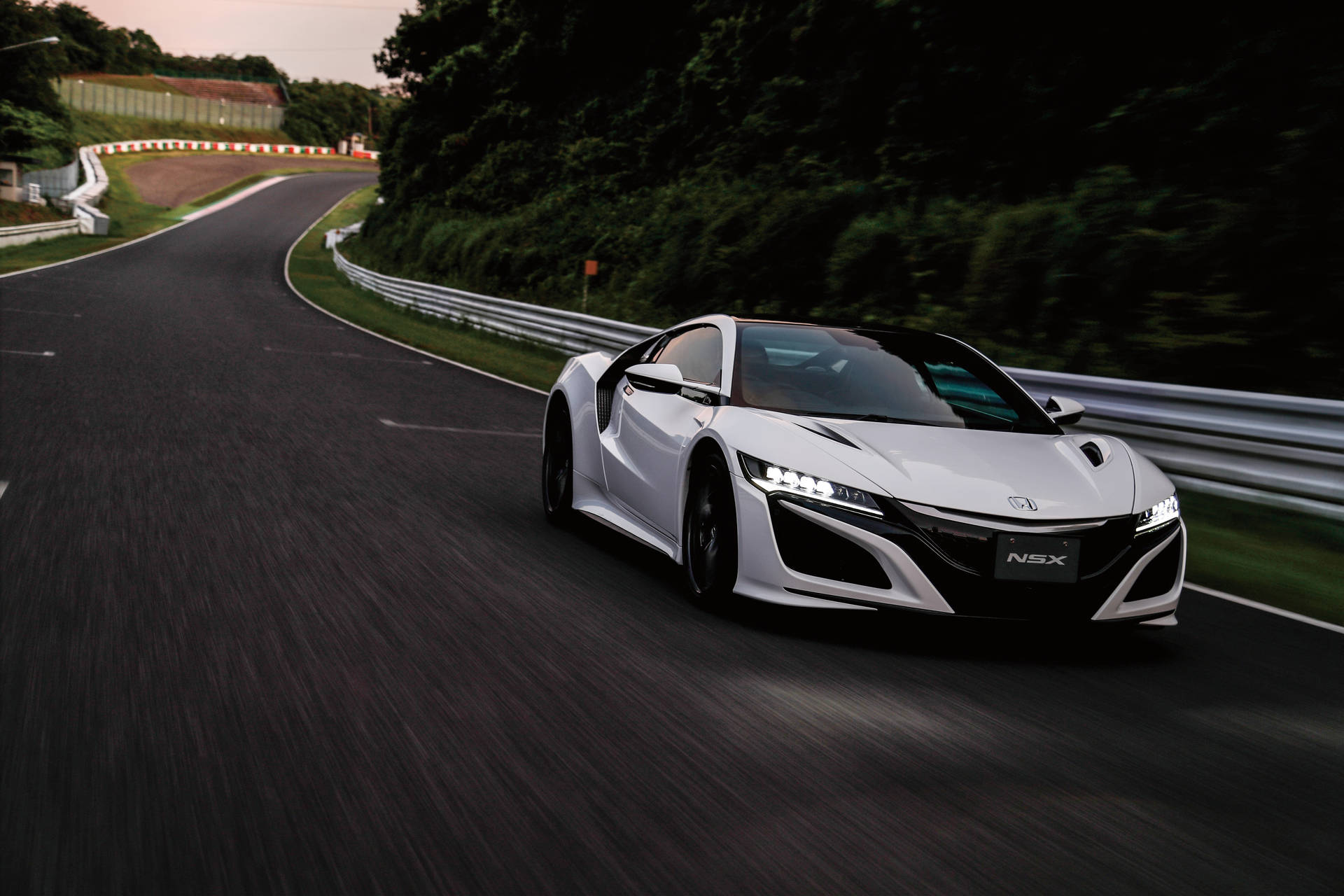 白色Acura NSX在黃昏時分的彎曲賽道上比賽