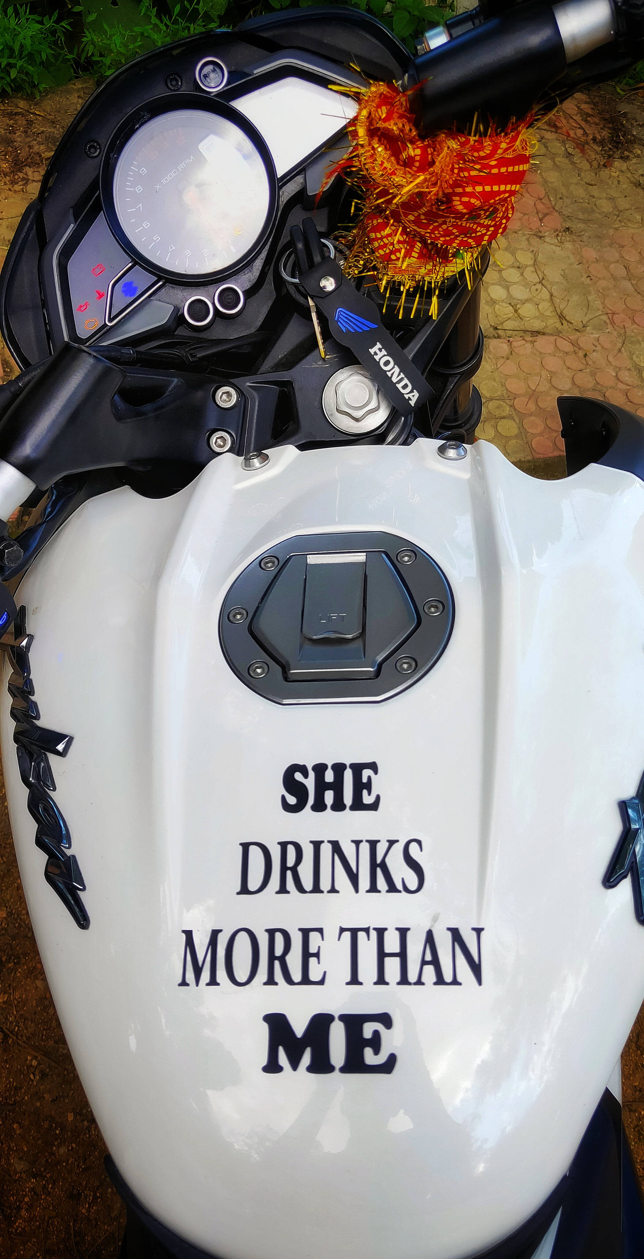 機車 桌布 壁紙 — 白色本田電單車油缸特寫，粗體字寫著「SHE DRINKS MORE THAN ME」，手柄上有紅橙色裝飾流蘇。