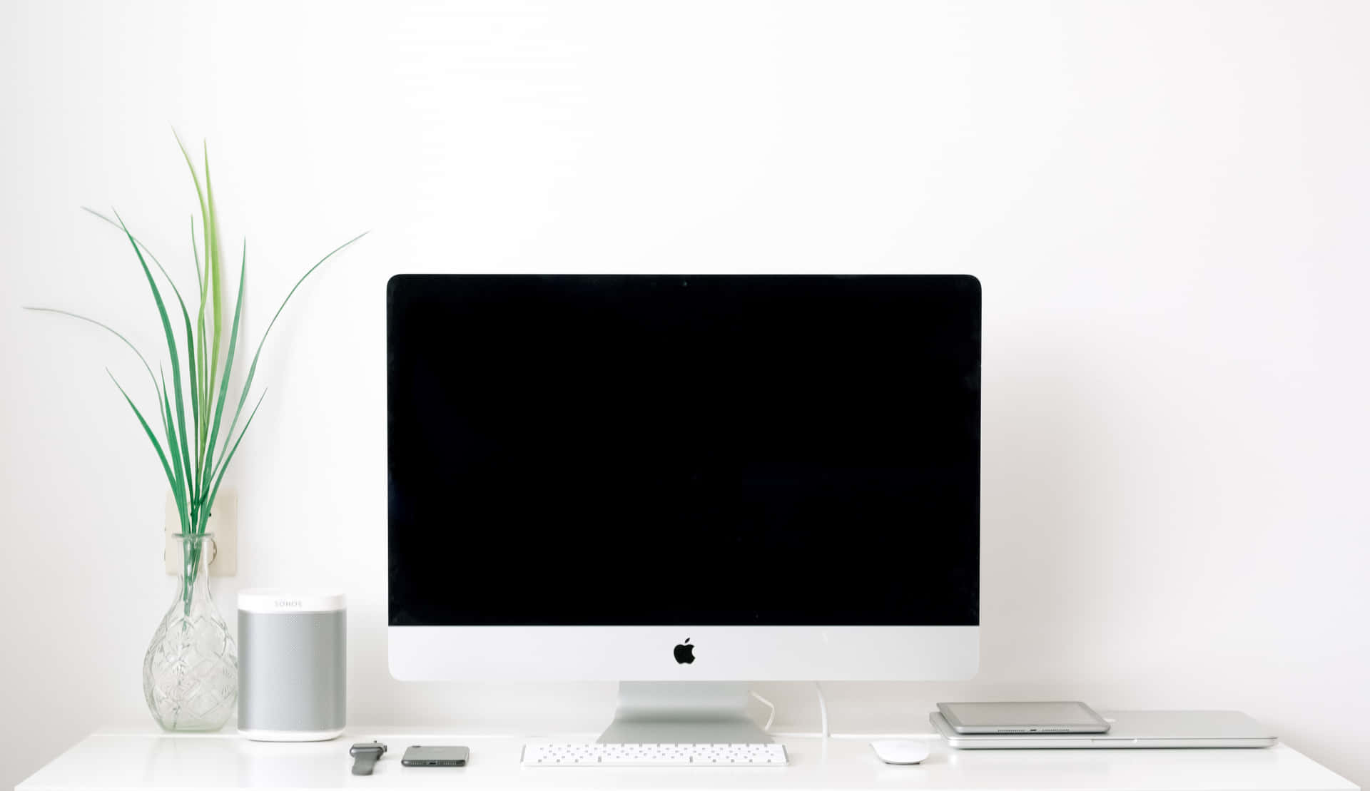 乾淨現代桌面，配有 iMac、植物和科技配件。