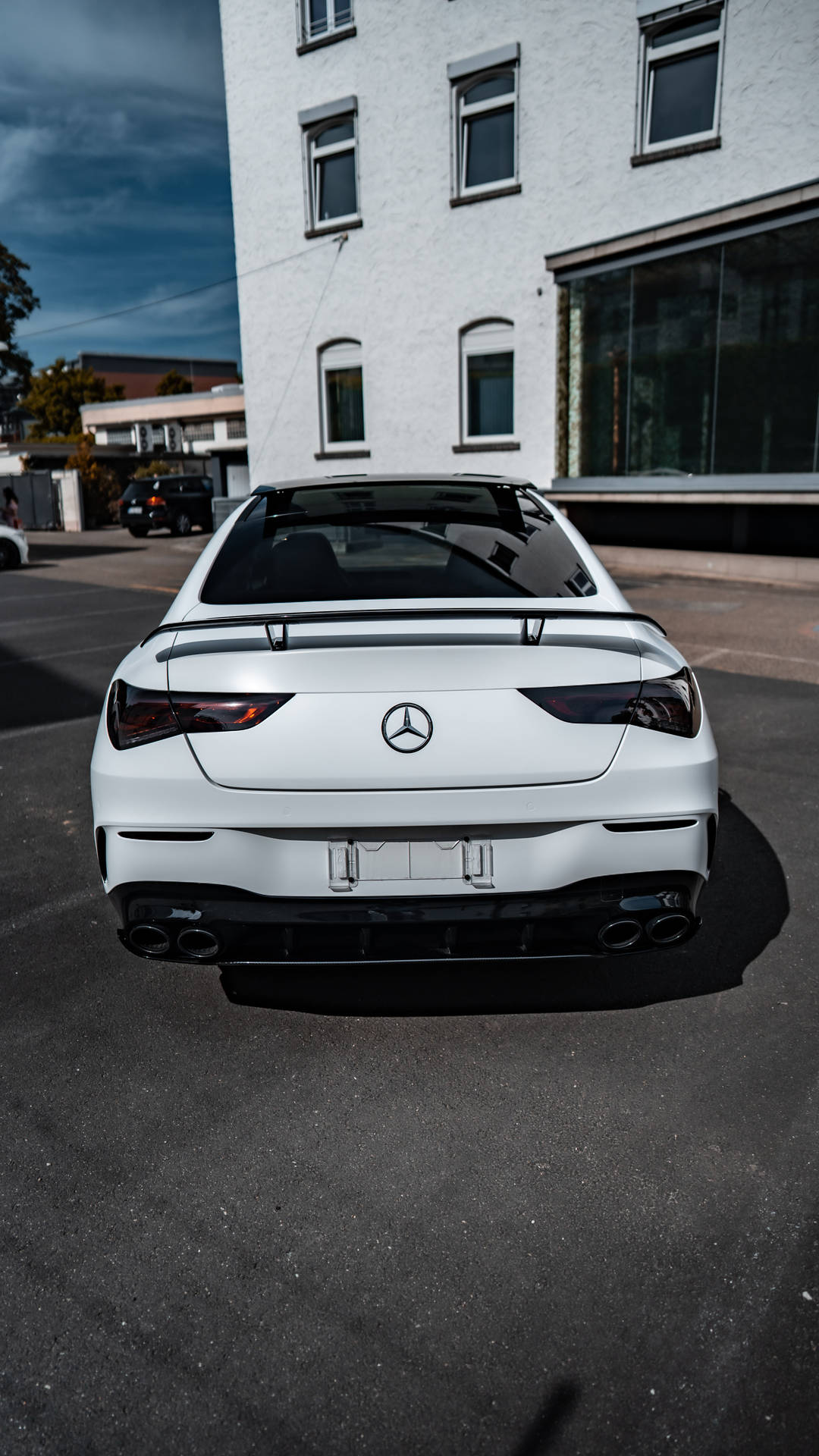 白色 Mercedes-AMG 跑車停泊在建築物附近的街道上。
