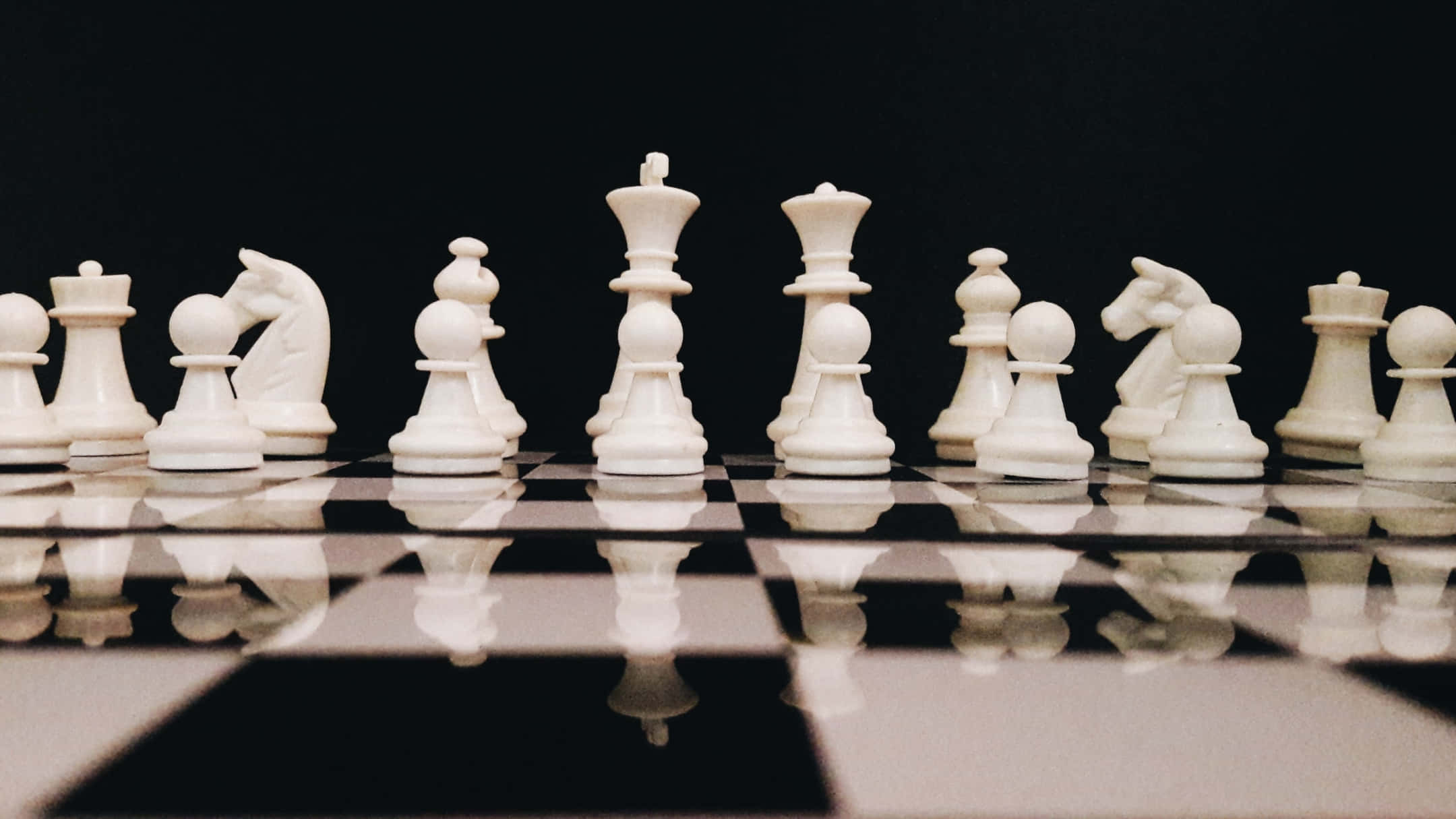 Chessboard 桌布 壁紙 — 白色棋子整齊排列在光亮的黑白棋盤上，反射清晰可見。
