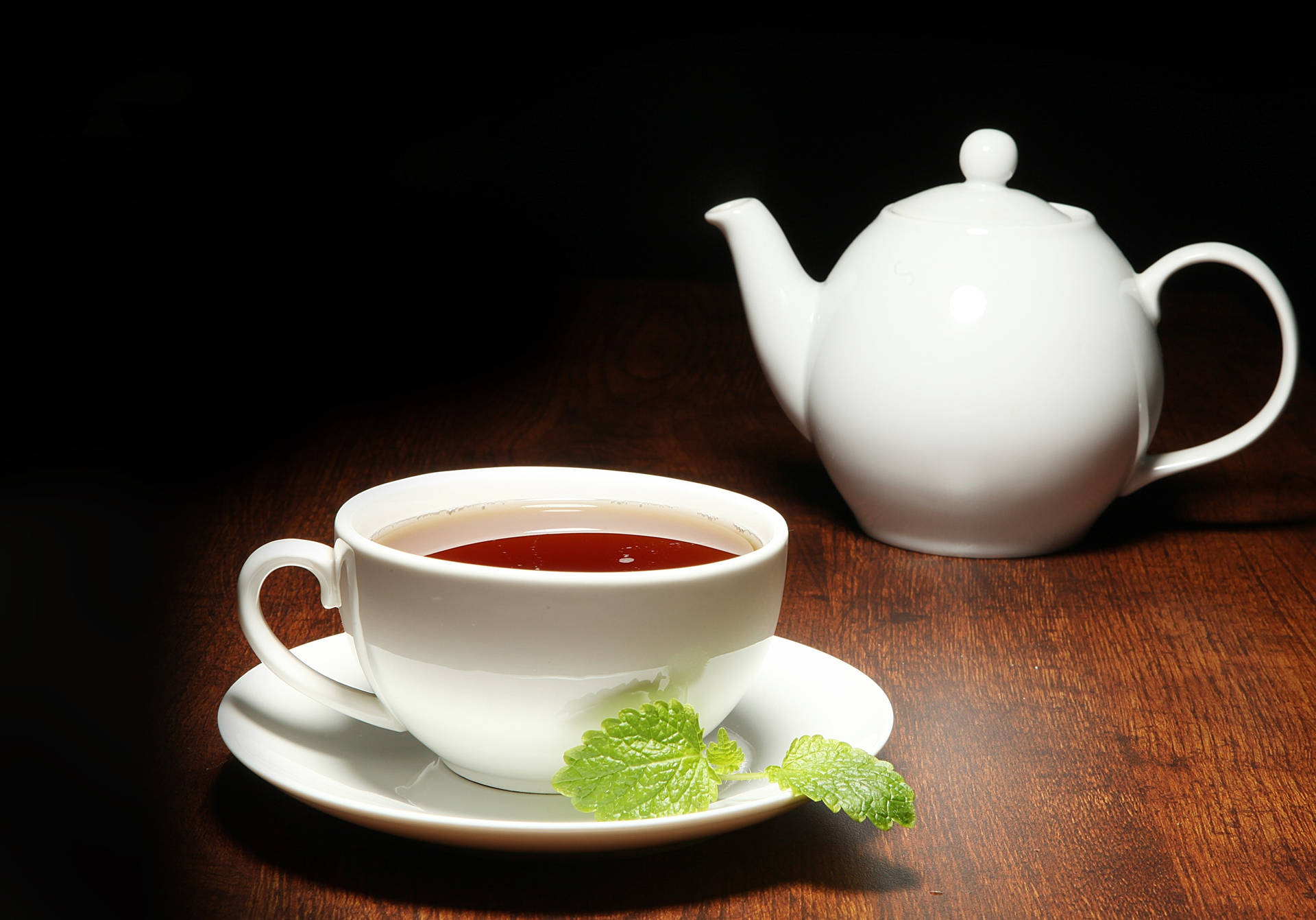 白色茶杯和茶壺配薄荷葉，木桌，聚光燈。