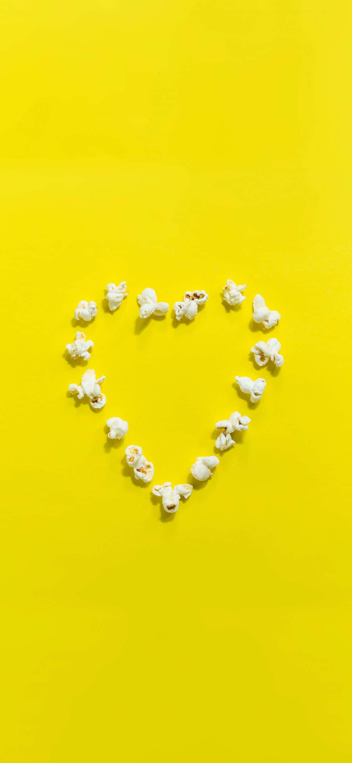 Yellow Heart 桌布 壁紙 — 白色爆谷粒在亮黃色背景上排列成心形。