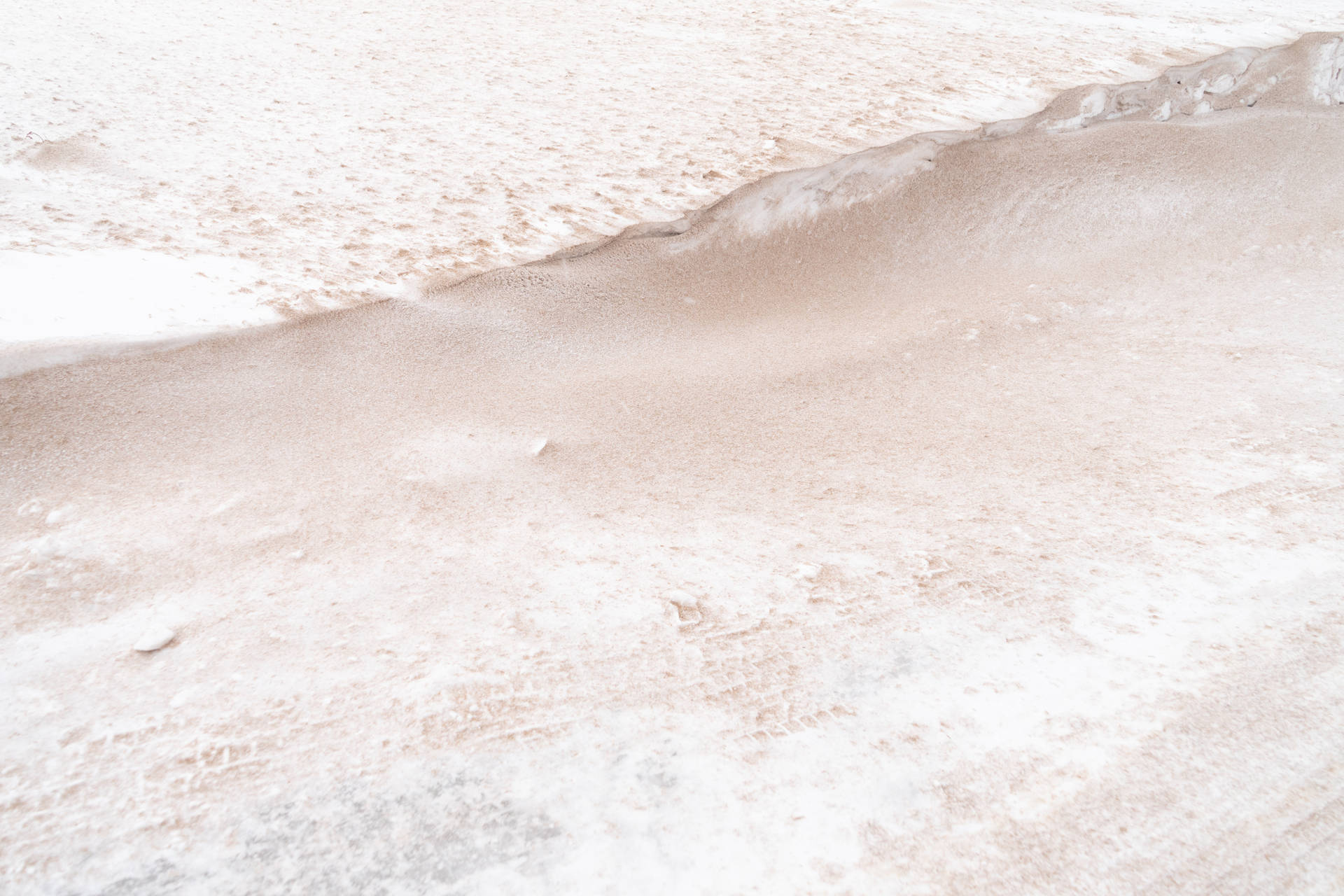 雪地特寫，帶有柔和粉紅色調及模糊腳印。