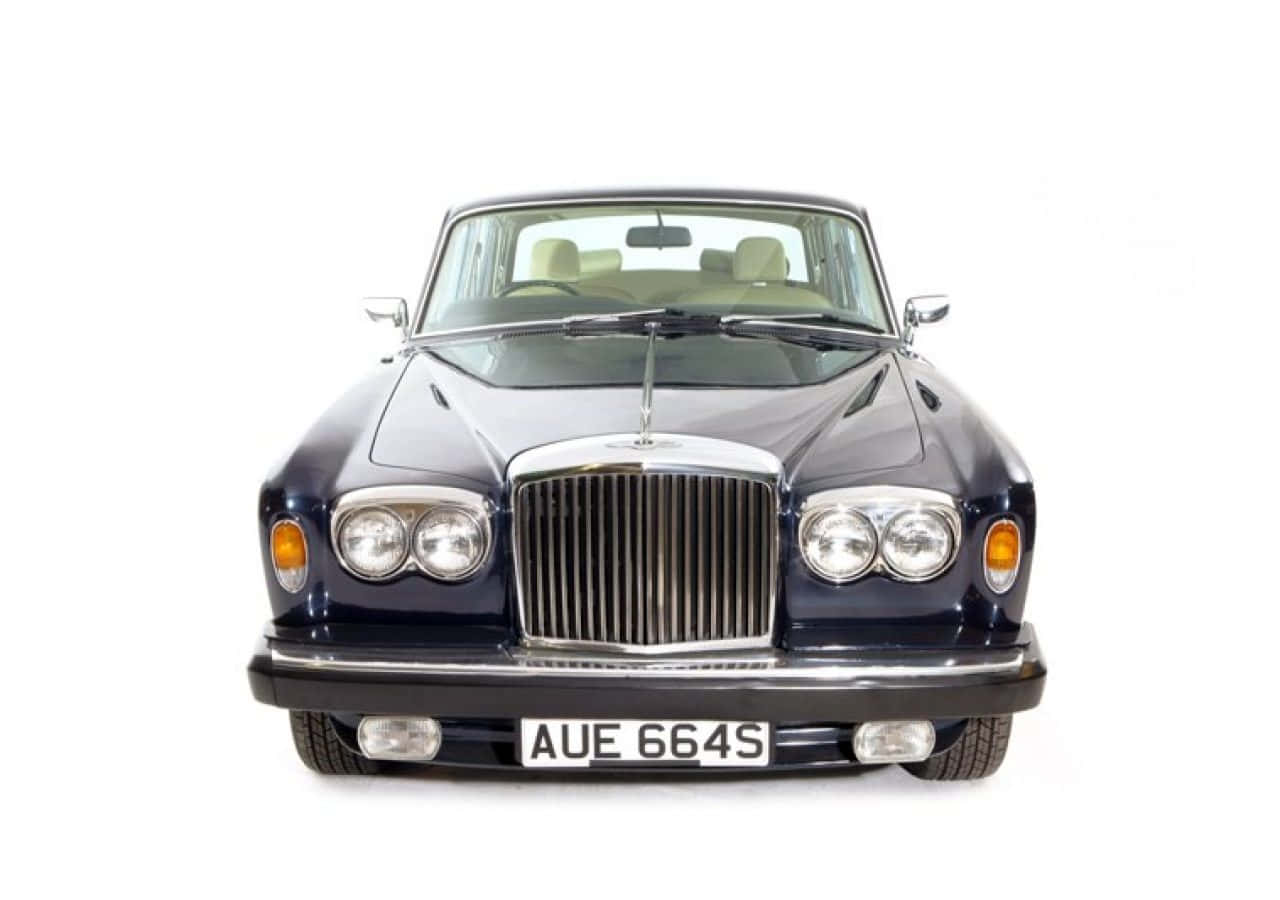 Bentley T2 桌布 壁紙 — 白色背景前，經典深藍色賓利的前視圖，配備鍍鉻格柵和奶油色內飾。