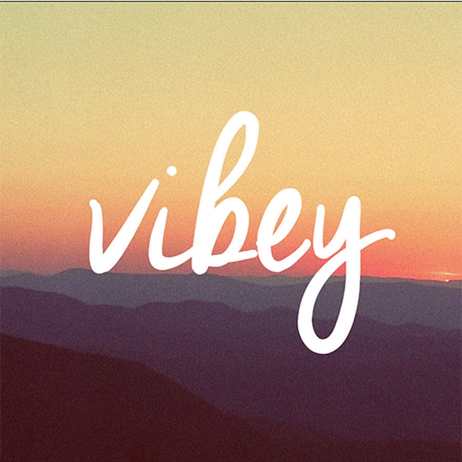 Vibey 桌布 壁紙 — 白色草書字體「vibey」漂浮在層疊的山巒剪影之上，背景是溫暖的日落漸變天空。