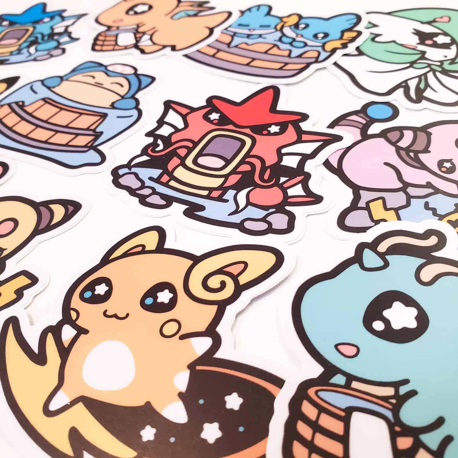 Pokemon Stickers 桌布 壁紙 — 白色表面上散落著色彩繽紛的卡通風格寵物小精靈貼紙特寫，包括比卡超等角色，採用可愛的Q版風格。