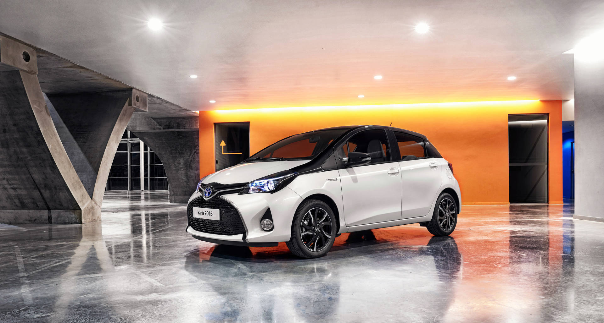 現代混凝土車庫中帶有橙色燈光的白色豐田Yaris 2018。