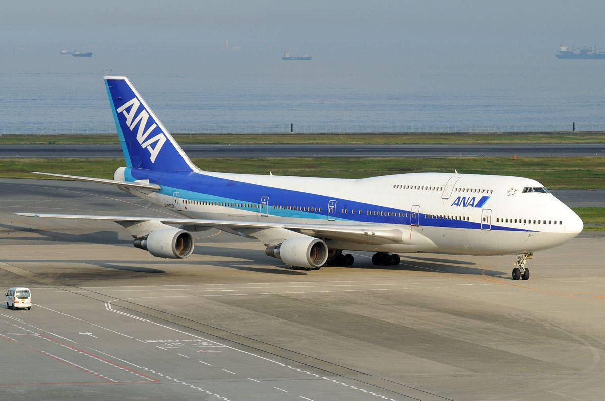 ANA波音747飛機在機場跑道滑行，靠近海洋。