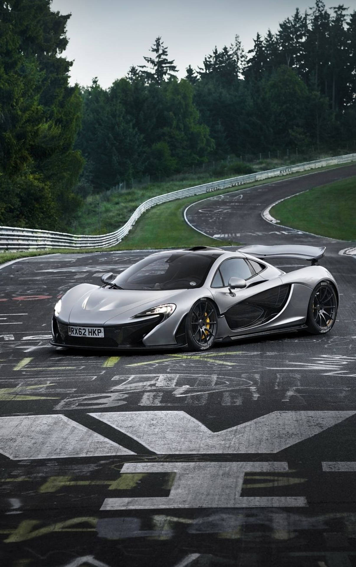 銀色McLaren P1在茂密森林環繞的彎曲賽道上飛馳。