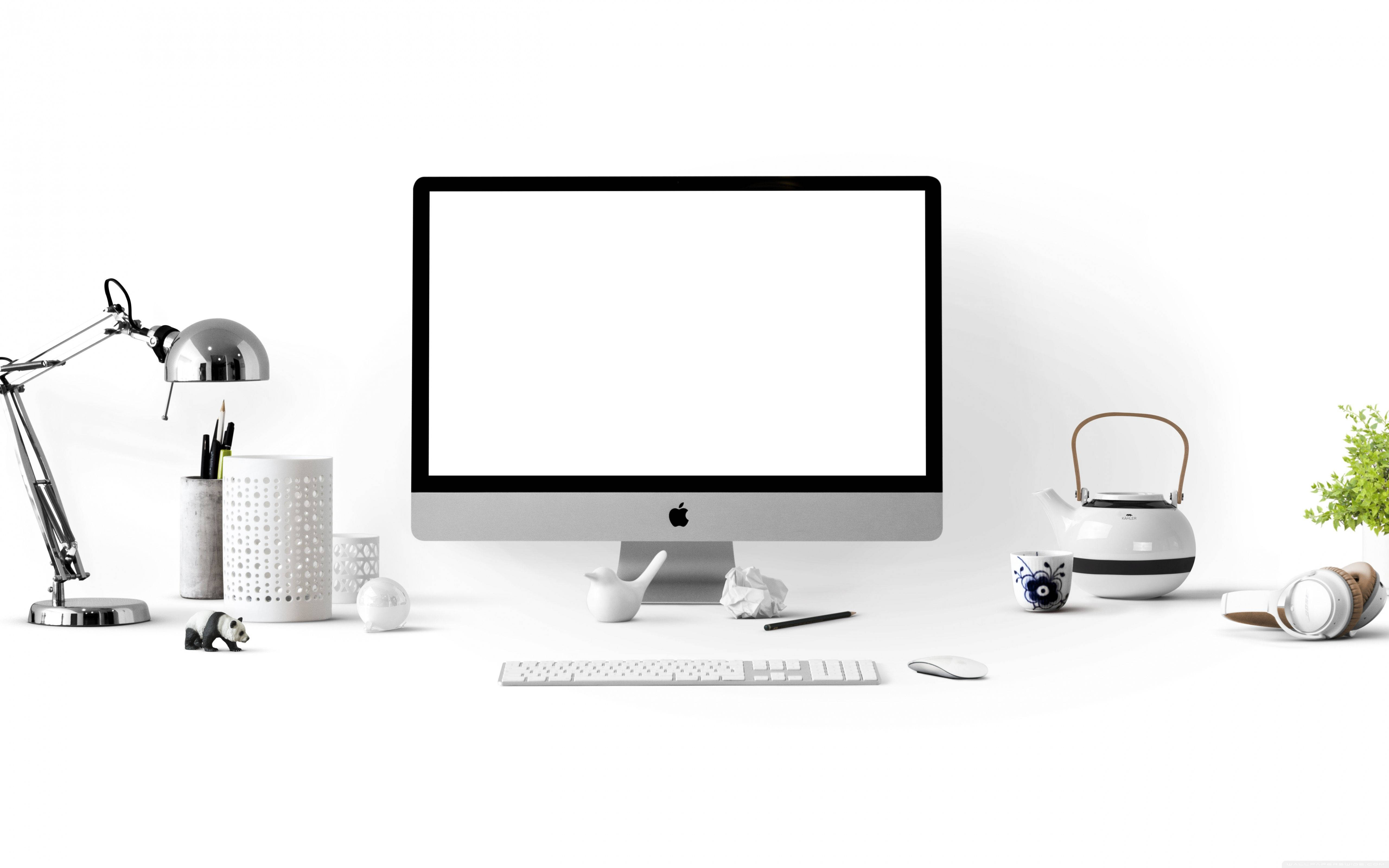 白色辦公桌上放置的 Apple iMac 壁紙 — 簡約白色桌面設置，配備 iMac 電腦，周圍有現代桌面配件和小型裝飾品。