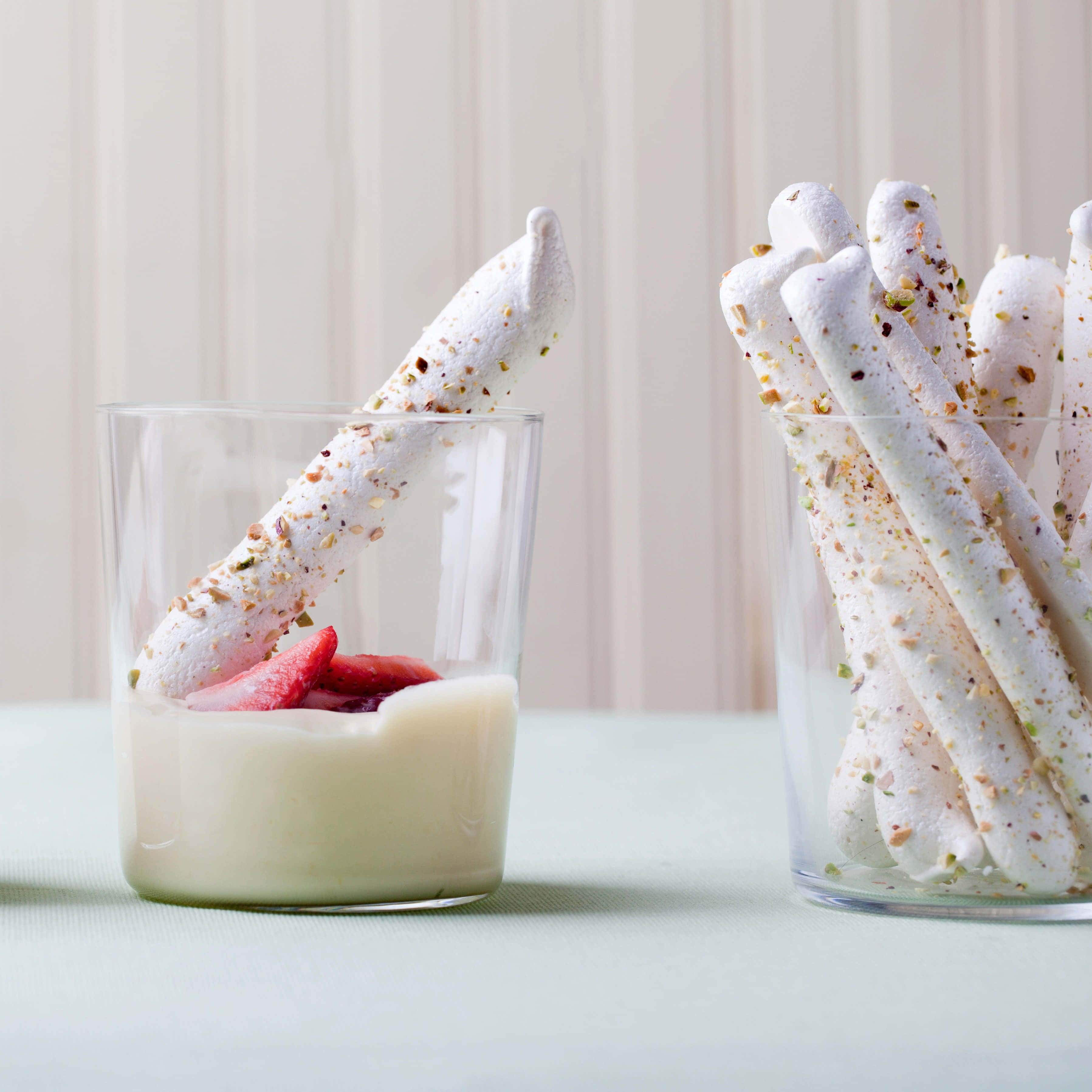 Meringue 桌布 壁紙 — 白色開心果包裹的棉花糖棒蘸入透明玻璃杯中的奶油白色布丁和新鮮草莓片。